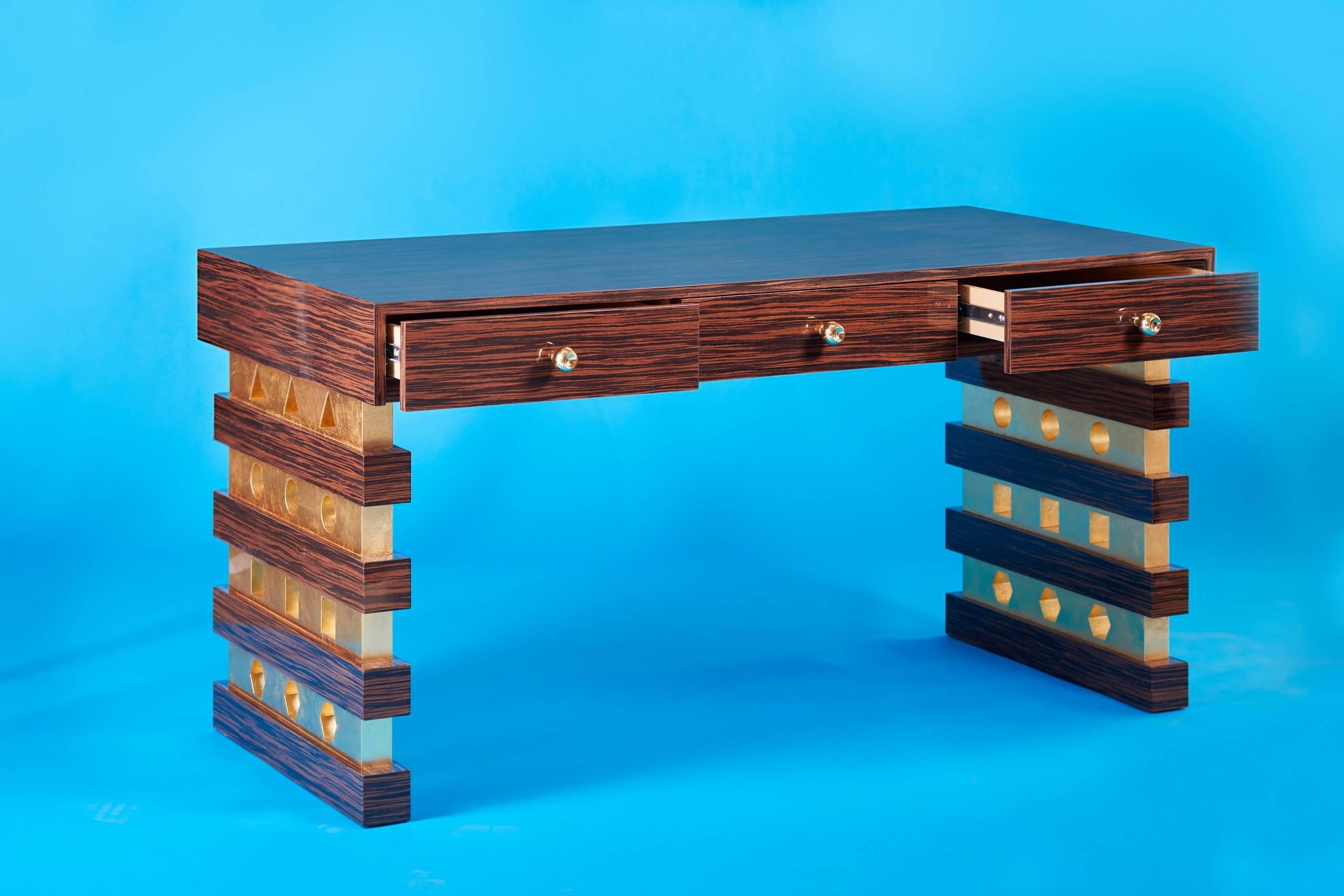 Der Shape Shifter Desk ist ein wunderschöner, handgefertigter Schreibtisch im zeitgenössischen Art-Déco-Stil.  Die Messingknöpfe wurden individuell angefertigt und auf Hochglanz poliert. Die Beine des Schreibtisches wurden mit Blattgold verziert, um