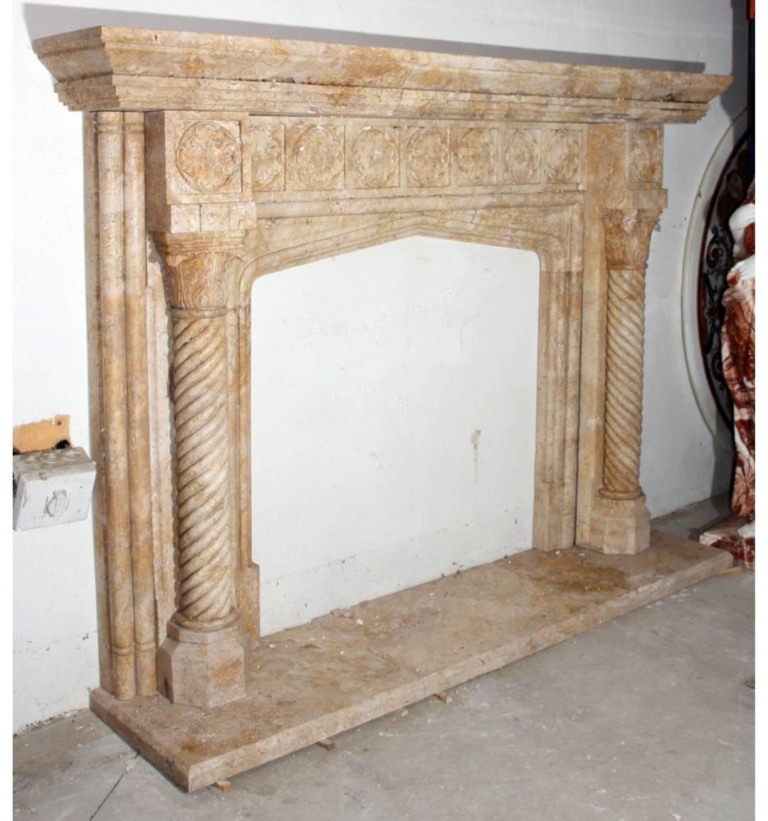 English style fireplace mantel hand-carved in Romano travertine stone. Flanked by two spiral salomonic columns and decorated with flower rosettes bass-relief frieze. 

Interior fireplace measurements: 103 cm x 105 cm.
 