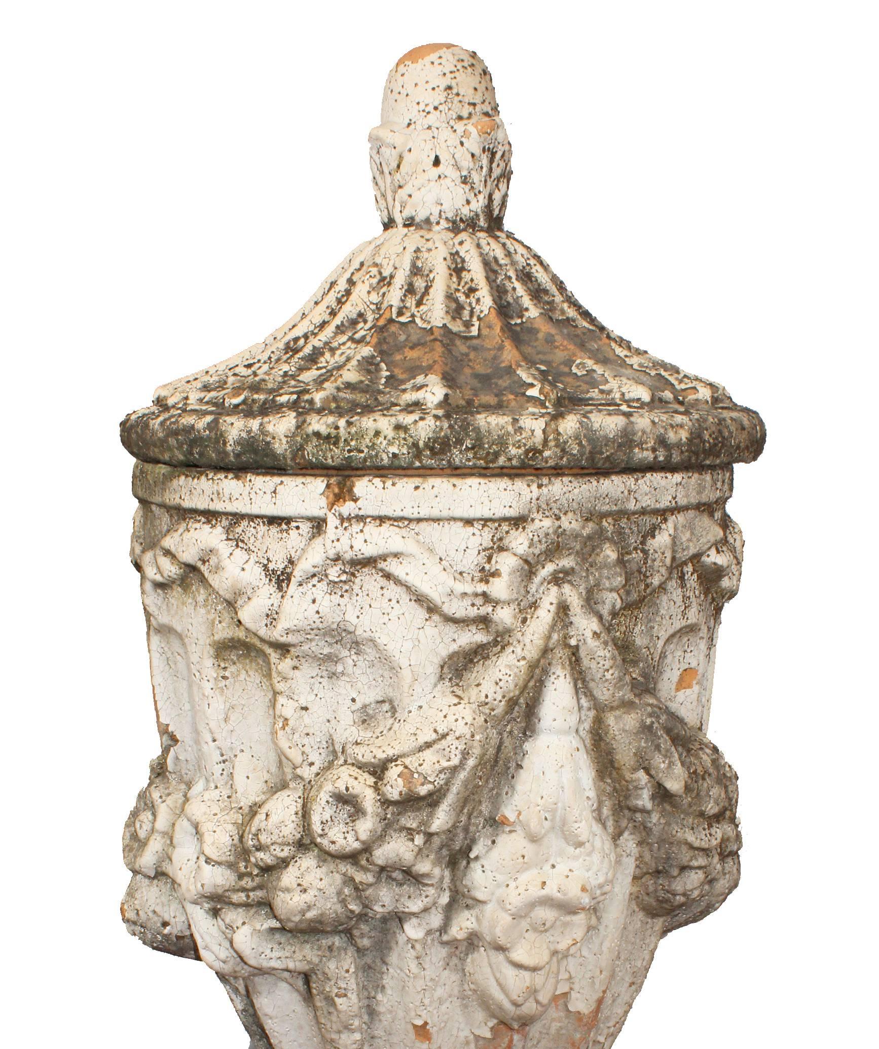 Classical style terracotta urns decorated with flower garlands.
