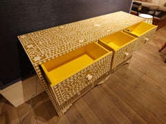 Credenza intarsiata con nove cassetti su sfondo color senape