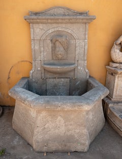 Fontana da parete in stile classico con vasca ottagonale in marmo scolpito.