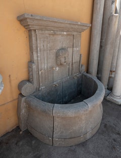 Natural Stone Wall Fountain with a Classical Mask and a Semicircular Basin.