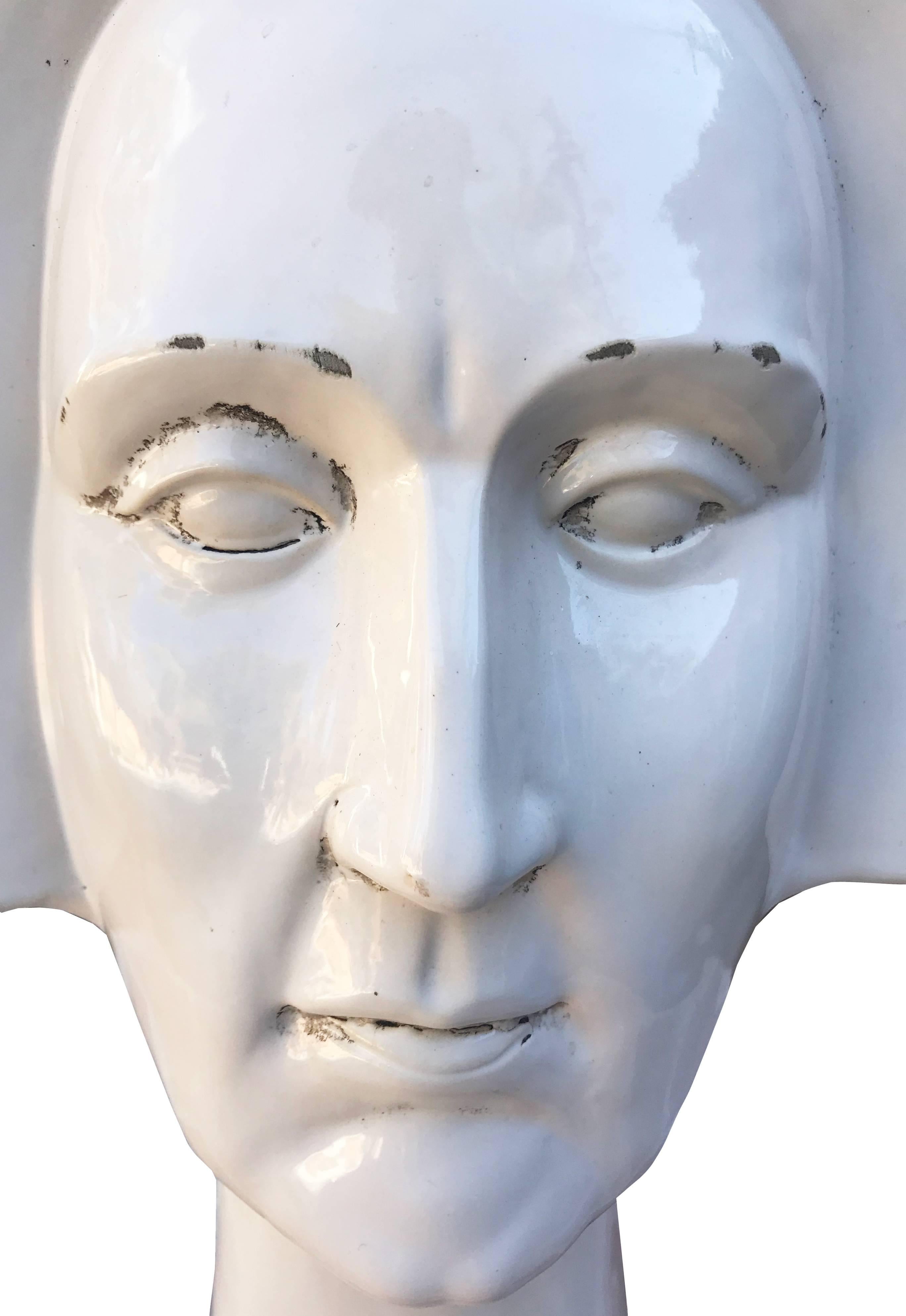 Highly realistic white glazed ceramic bust of person with a straight haircut. 
 