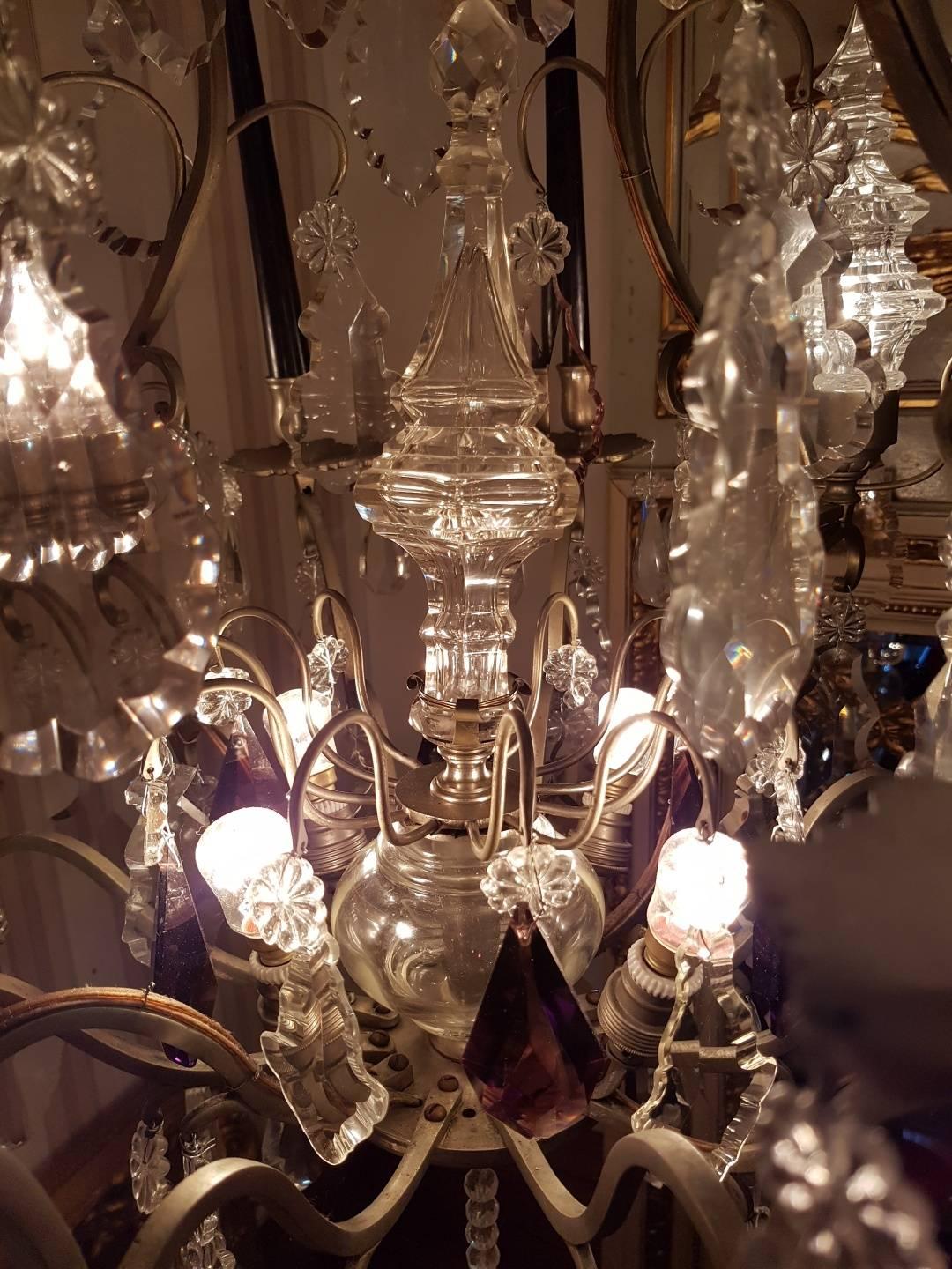 French chandelier in bronze with silver patina. Four lights at the bottom, four lights in the top and four lights within the pinnacles. In addition eight candles. Beautiful crystals including pieces in a soft purple color.
 
