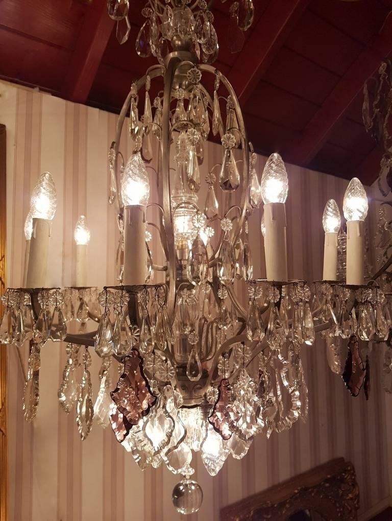 French chandelier with 16 lights. Ten candle light points, one light under the large pinnacle in the center and 5 downward targeted. Beautiful crystals also in purple. Frame bronze with silver patina.
This is just one of the collection of 1000