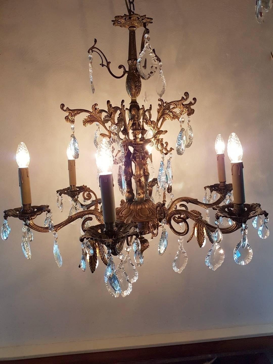 Spanish bronze chandelier with glass and nice ornaments. Three children are shown on the chandelier's frame. Six lights and three lights at the bottom.
This is just one of the collection of 1000 chandeliers, ceiling lamps and wall lightning.