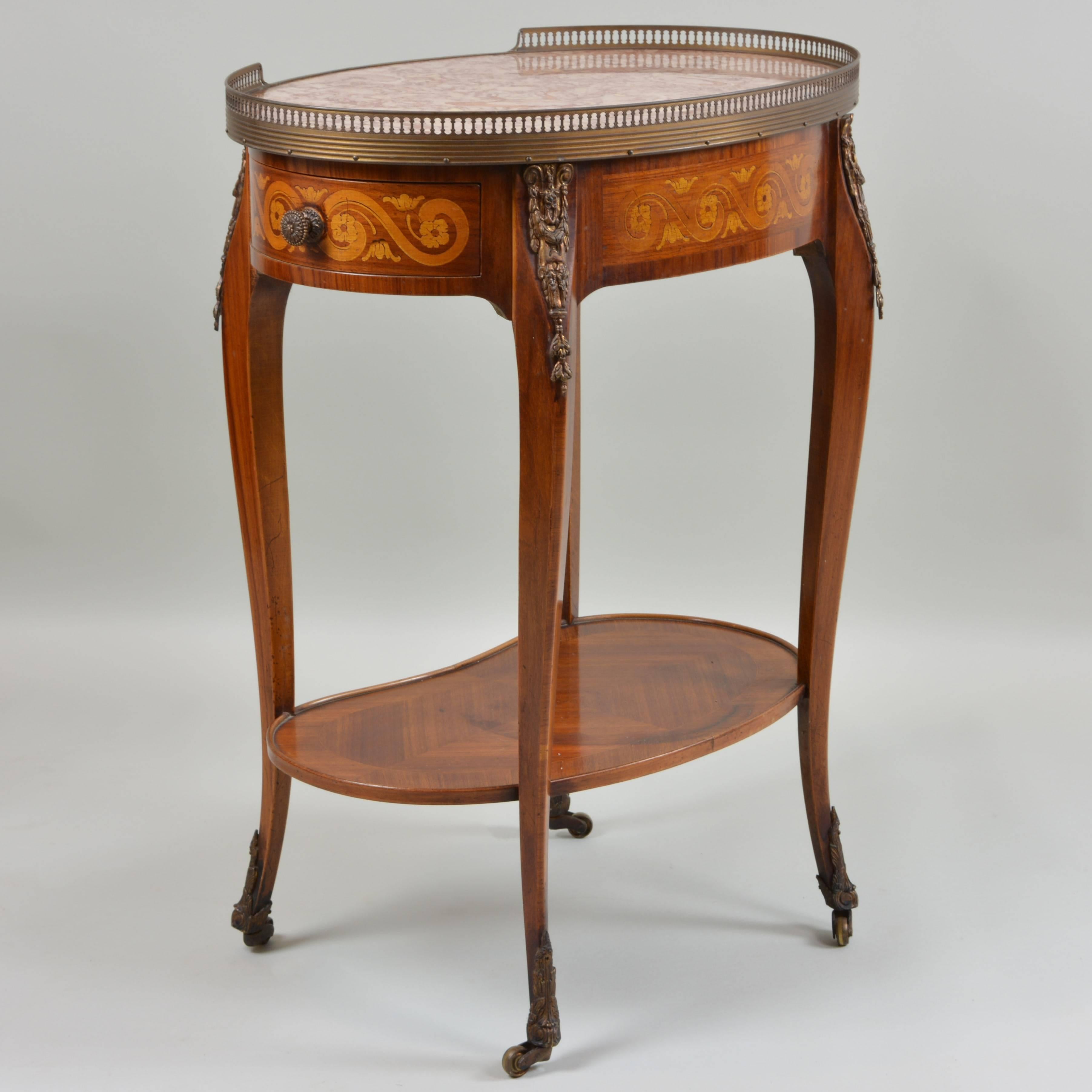 We call this our "Kidney Table" because of the uniquely shaped undershelf that presumably gives clearance for a domestic staff member's legs. Its gorgeous oval top appears to be crafted of native Rouge des Pyrenees quarried marble from
