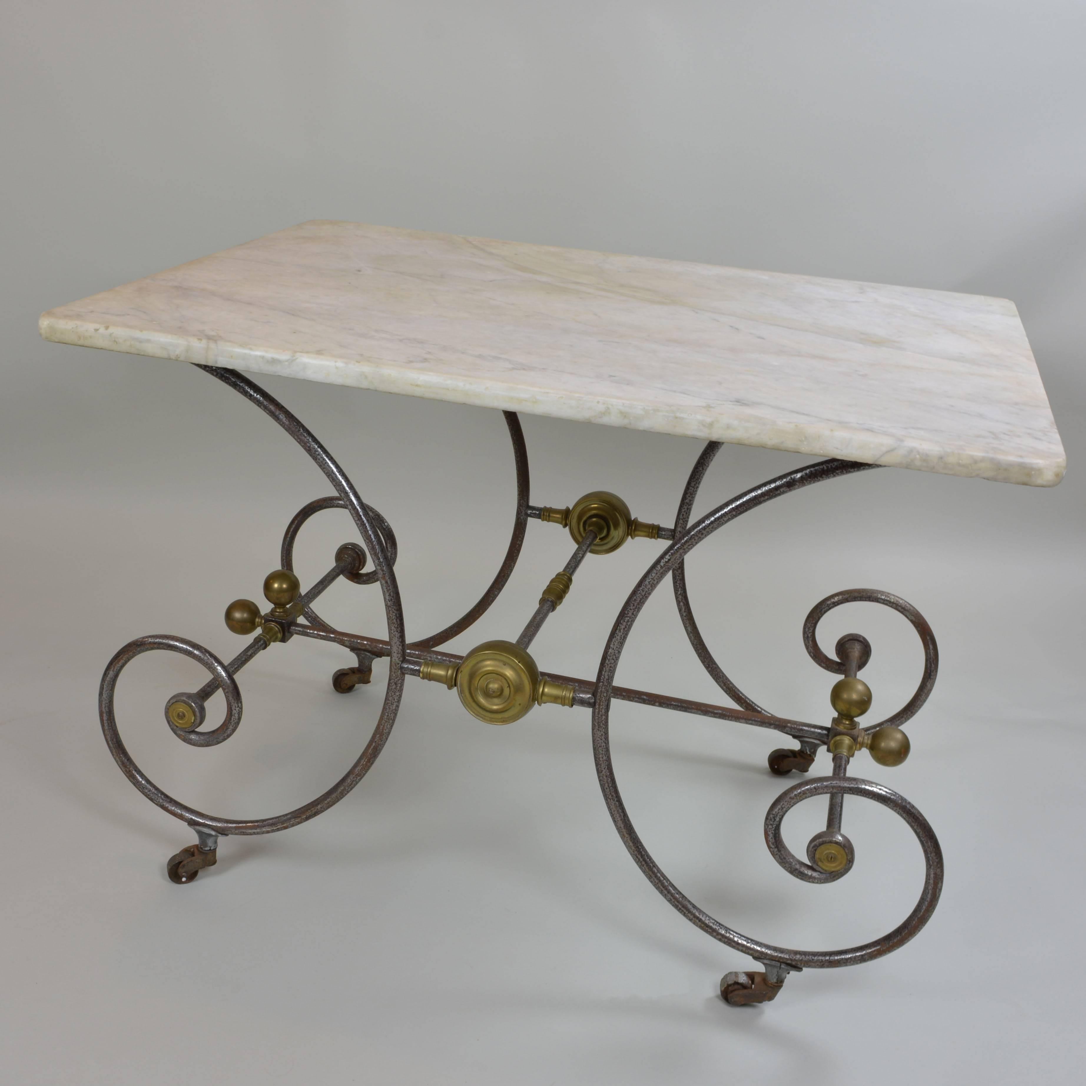 Lovely old pastry maker's table from France, circa 1810. Rich, cream-colored marble top; graceful wrought iron frame with brass accents and casters. Light patina of rust adds to its Old World charm. 

Bakery tables were often used in exclusive