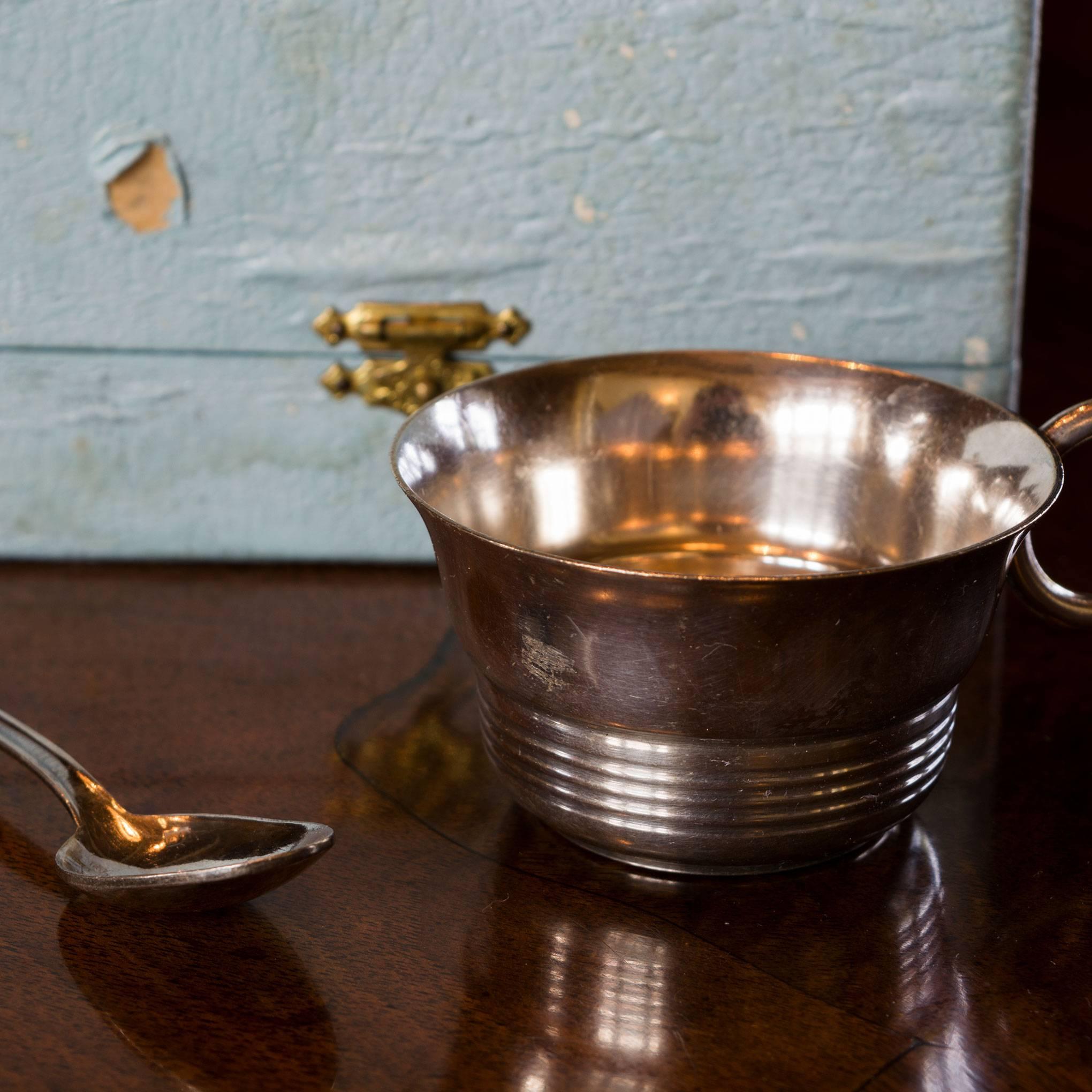 This lovely set is one that will be treasured for generations. The cup has a slightly fluted top with a simple ring handle. There simple ring design continues around the bottom of the cup. The accompanying spoon has a simple design on the handle.