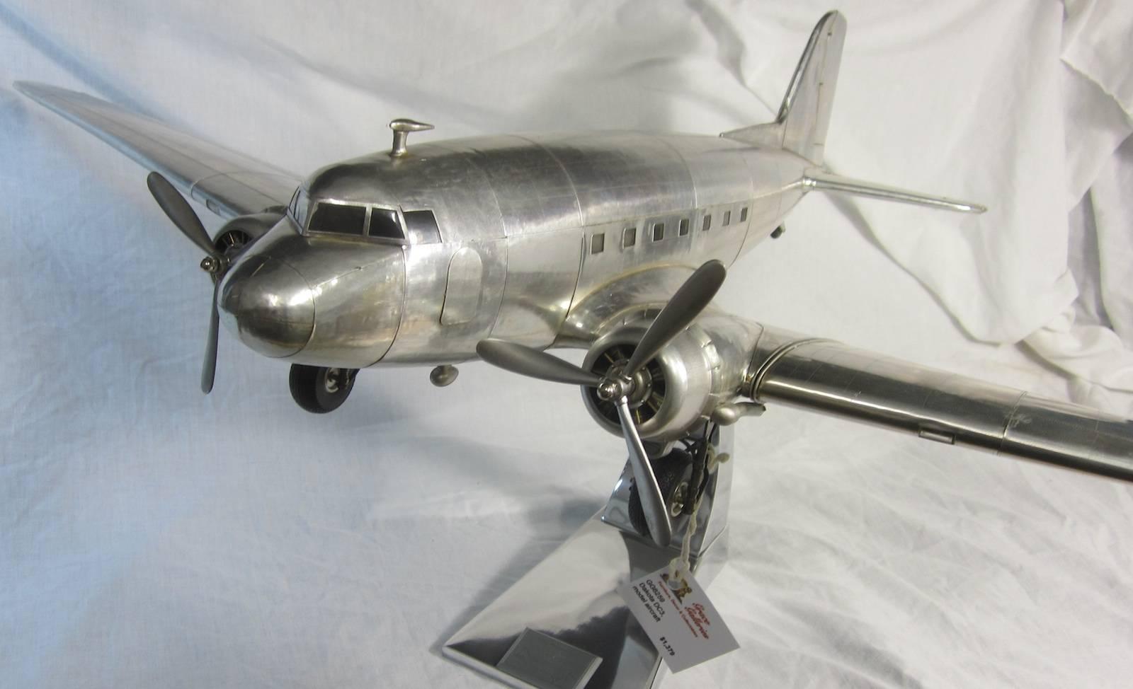 Dakota DC3 aluminium 1935 model aircraft,
On a display stand,
Aircraft measures 64 x 97 x 17cm
41cm high on the stand.