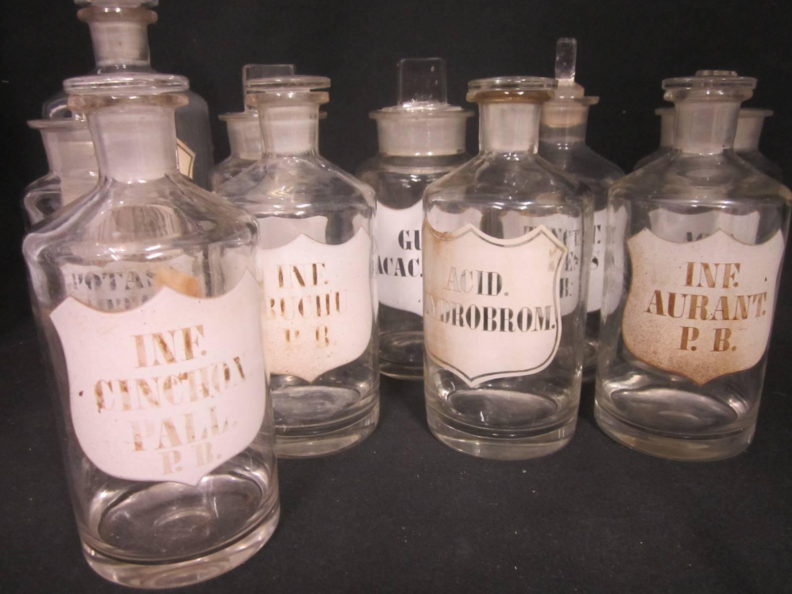 10 x Apothecary bottles, glass stoppers, enamel labels, from a 1950's Brisbane, Australia, pharmacy, 1 A/F Lycopodium has a chipped rim, 
They range from 19-24cm high