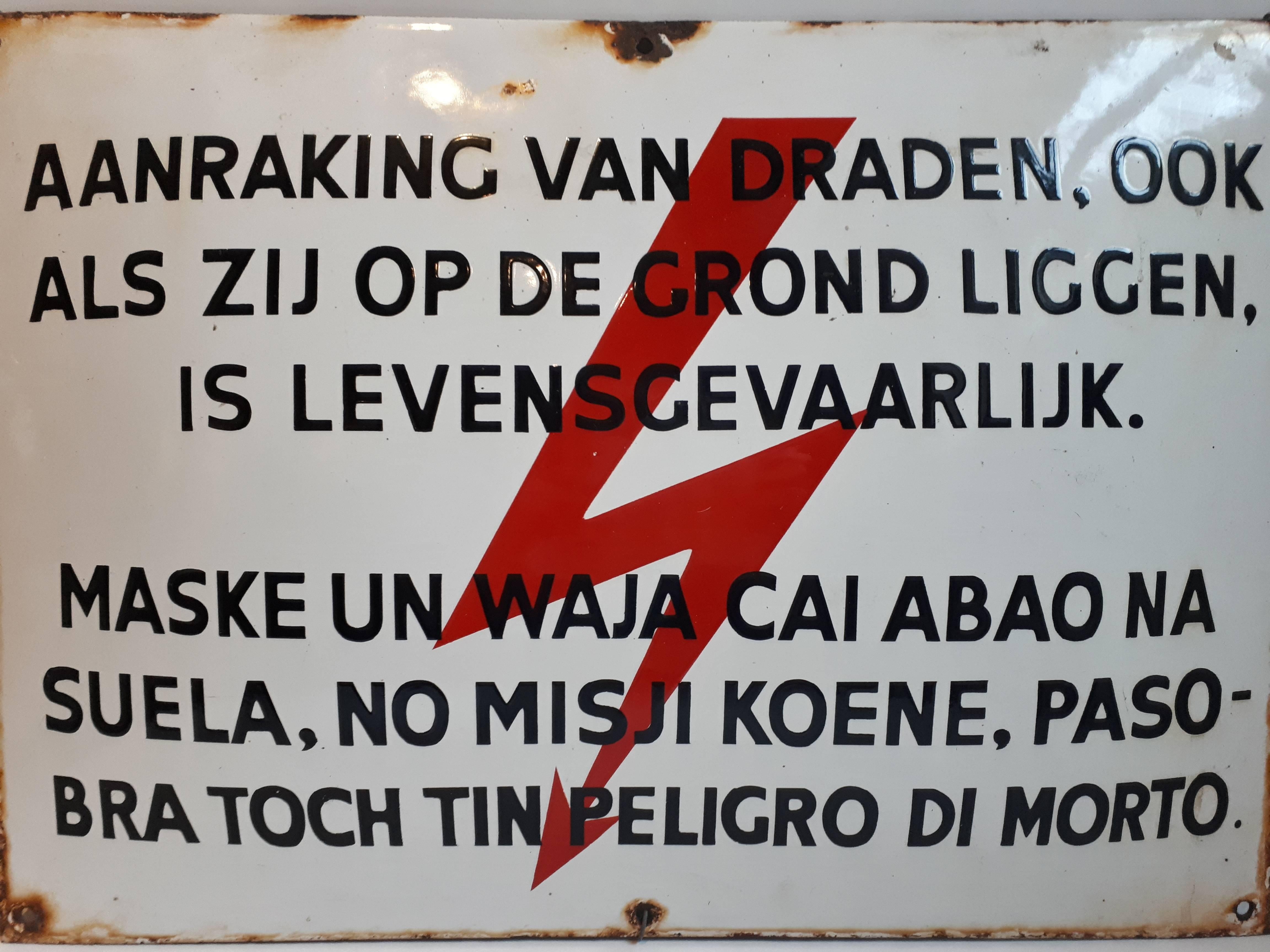 An orignal enamel sign that was used as a warning for the people on one the ABC Islands. 

Papiamentu (or Papiamento) is a mixture of Spanish, Portuguese, Dutch, English, French, and it also has some Arawak Indian and African influences.