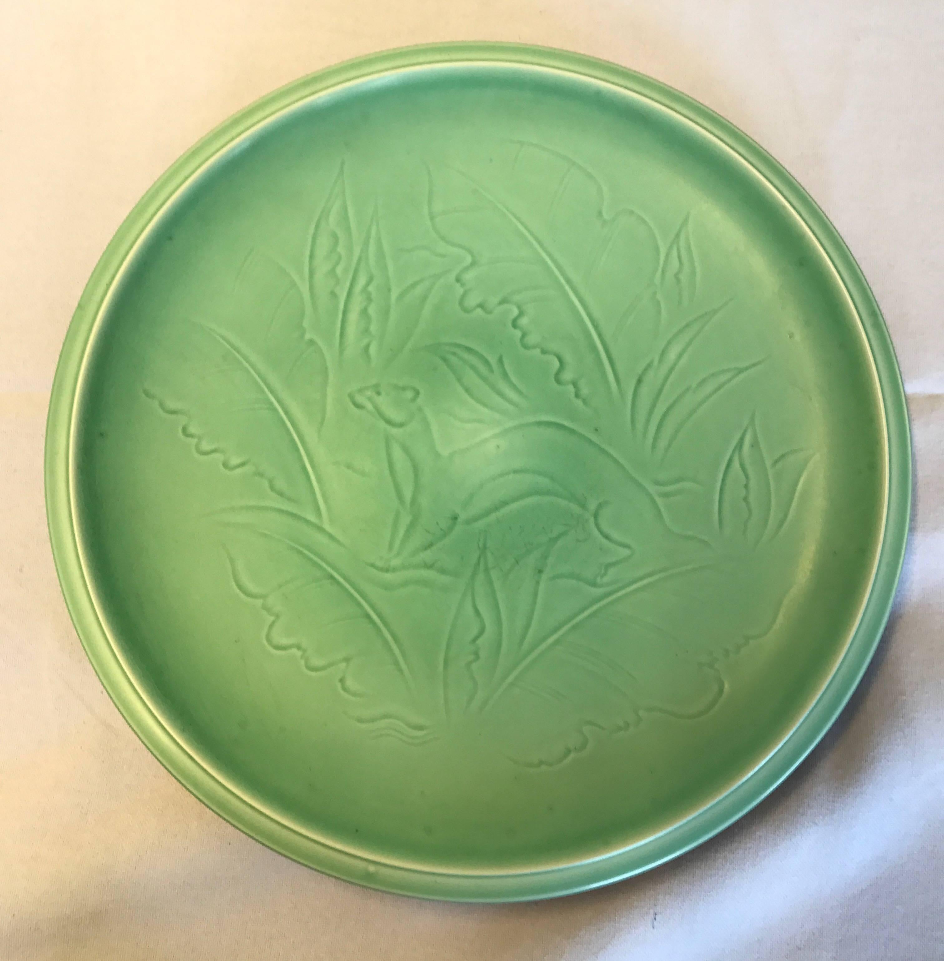 Large stoneware dish in soft green glaze, with a motive and a dark brown glaze at the back, designed by Nils Thorsson and made by Aluminia Denmark. Measures: Diameter 36 cm, height 4 cm. in very good condition.