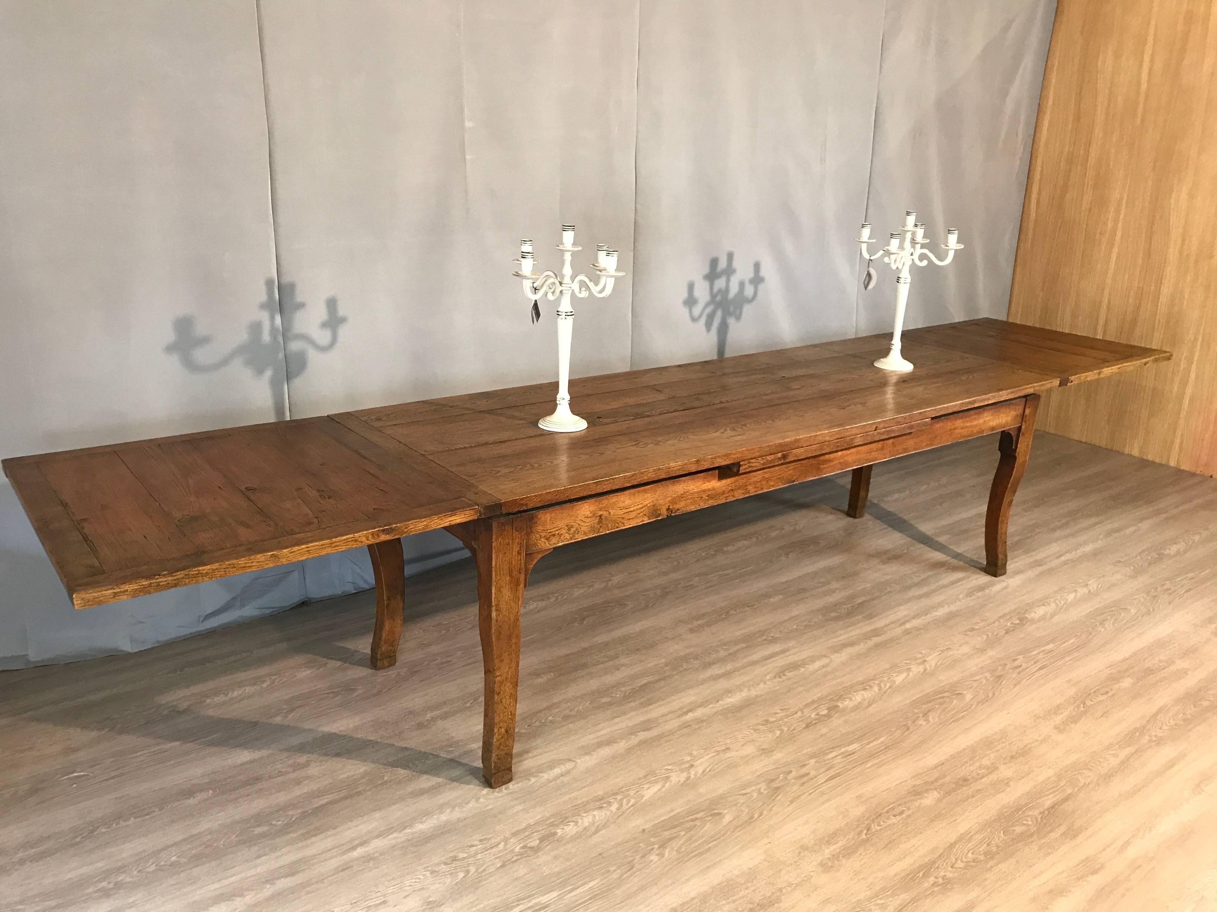 Substantial late 19th century oak French farmhouse double draw-leaf table. The table sits on a sturdy base supported by chunky cabriole legs raised on a later hoofed foot, which allows a good 24