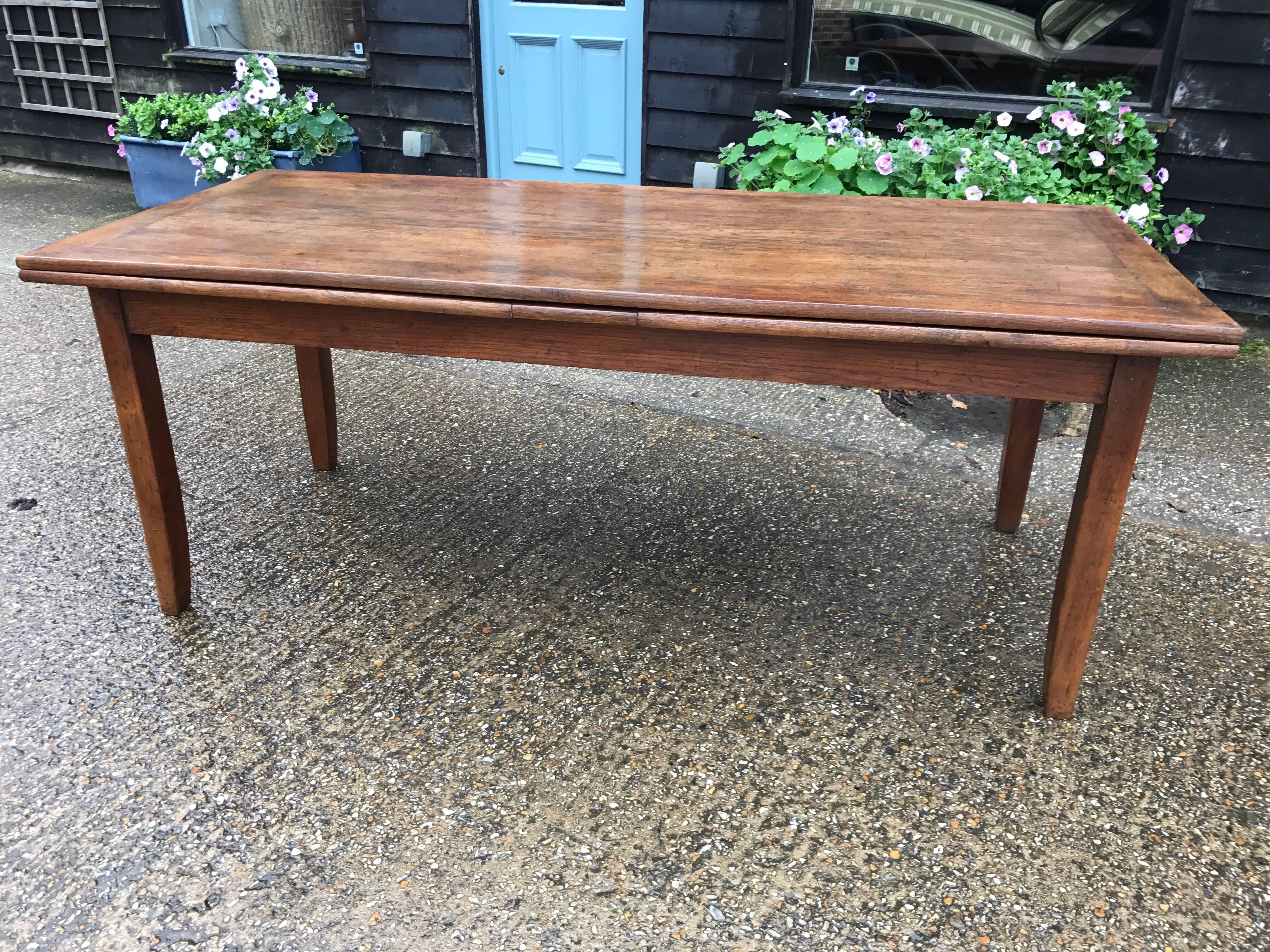 Antique oak double draw-leaf table, circa 1840 with wonderful features. The table has a four plank top framed all in beautiful French country oak. The two extending leaves are also framed to match the top beautifully. The frame is supported by four