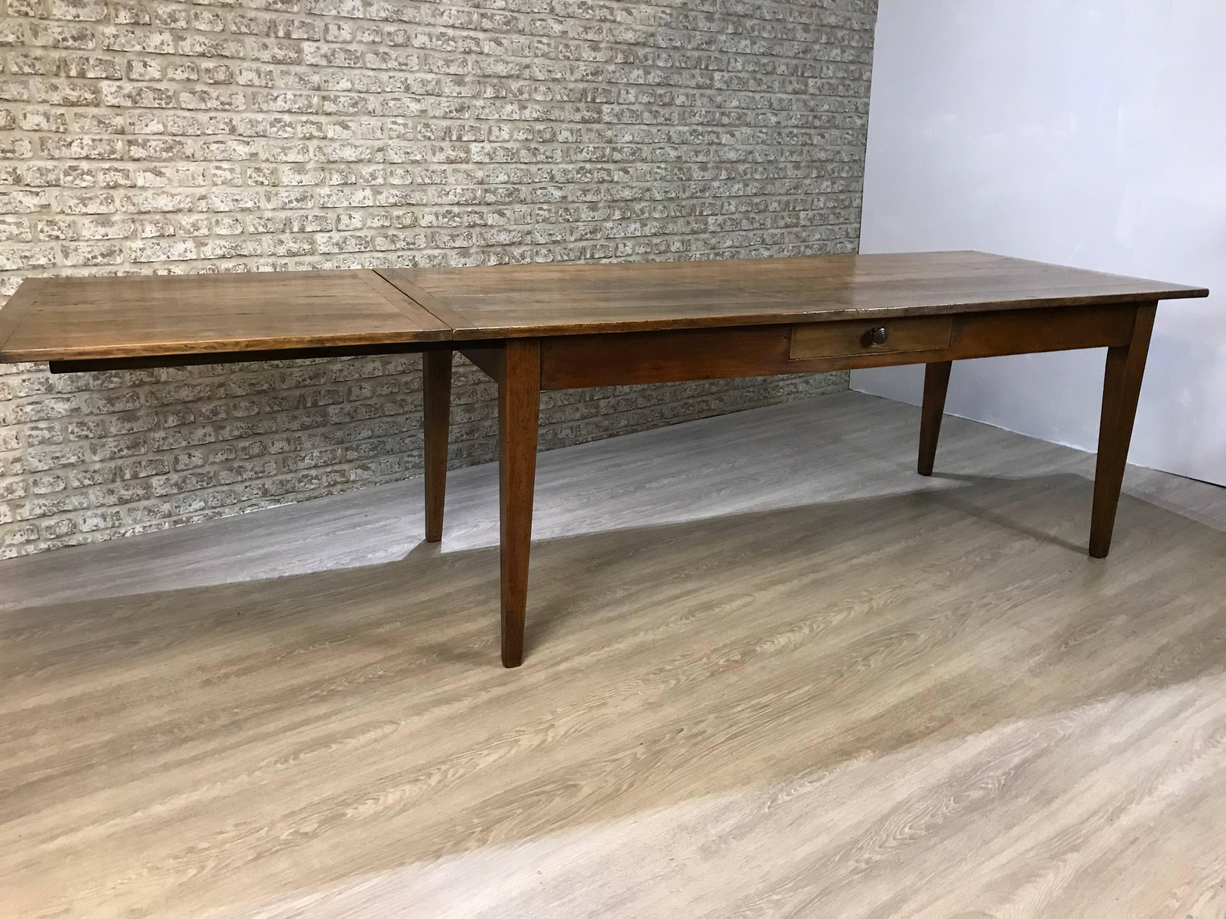 Lovely wide antique cherry farmhouse table with extension leaf. The has a four plank top with cleated ends and sits on a sturdy frame supported by four tapered legs. The slide works on two strong bearers and can easily be stored away when not in use.