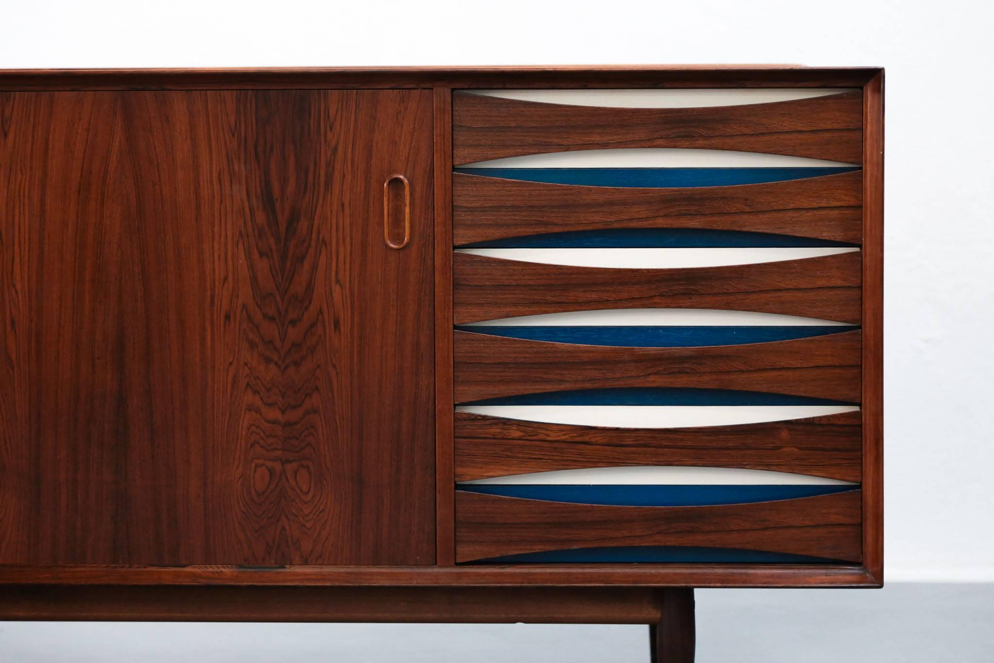 Rare sideboard from Arne Vodder. Two sliding doors with white and blue drawers on the side.
Produced by Sibast, Denmark.