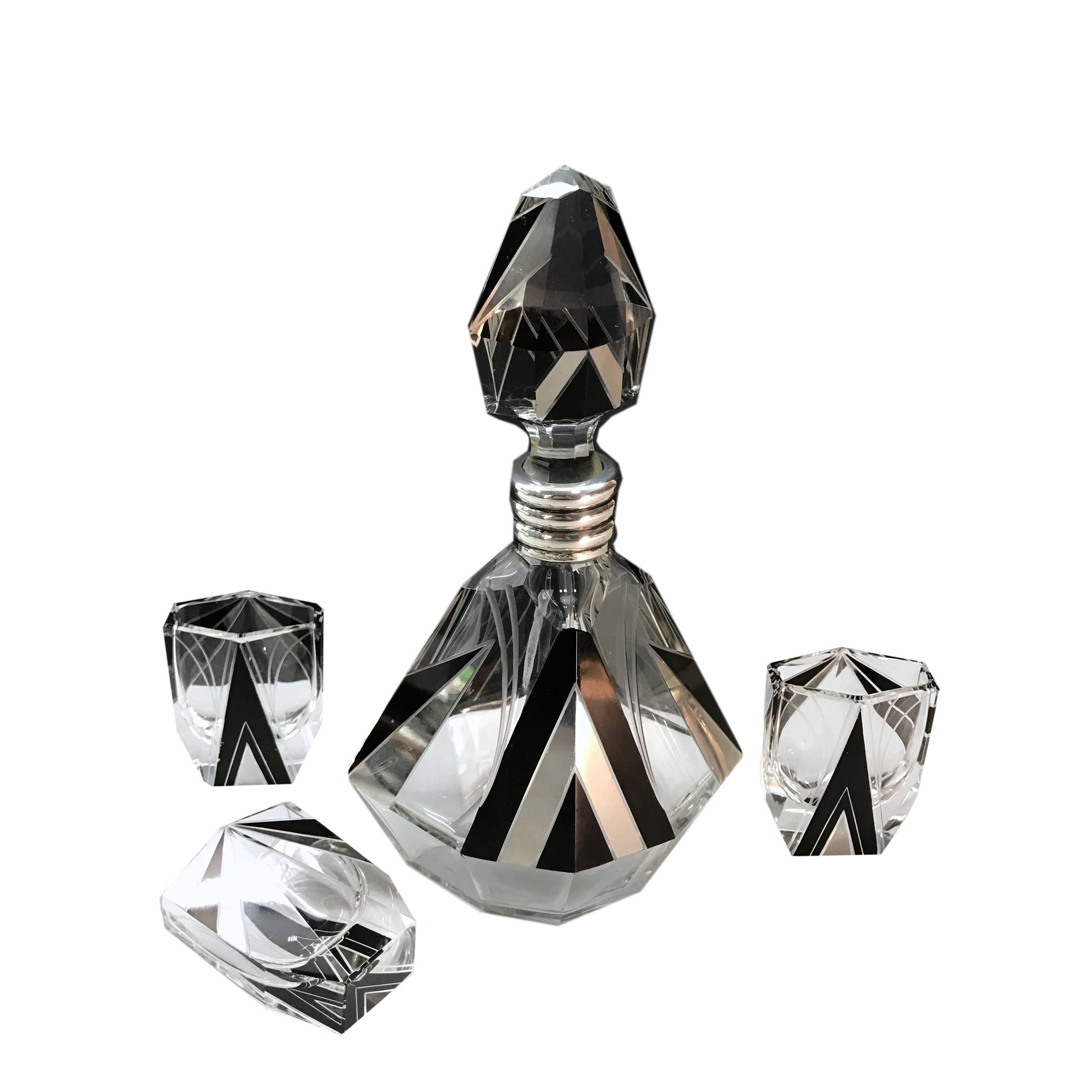 A 1930 decanter and three small glasses by Karl Palda Art Deco with a faceted shape, engraved and enameled. Finishing in 800 silver and silversmith punching. No chipping.
