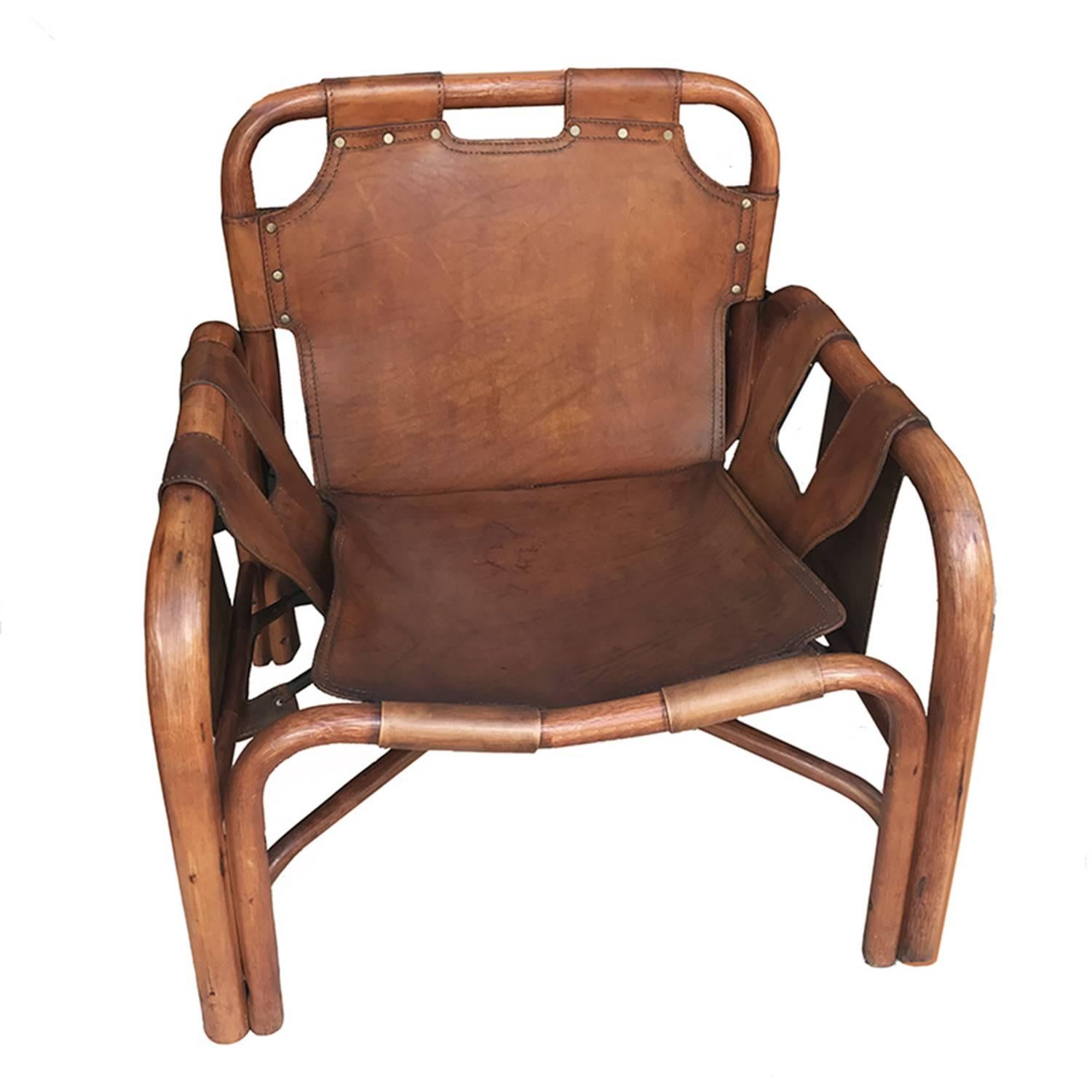 Italian Mid-Century Modern rattan and stitched leather lounge chair by Bonacina featuring elegant leather strap construction in the midst of an open framework.
