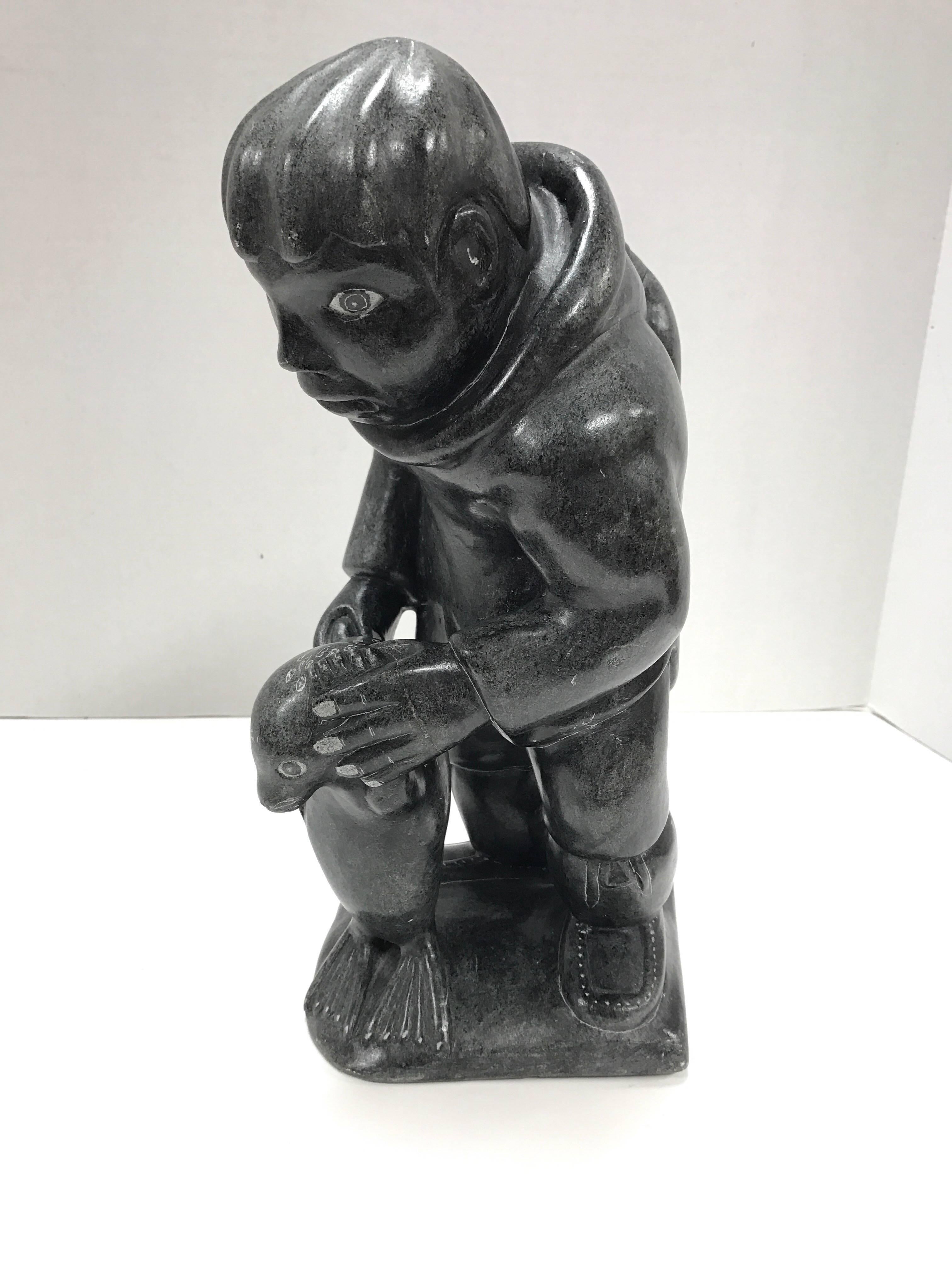 Inuit heavy soapstone sculpture showing Eskimo hunter with prey. Hallmarked at bottom of base with tag that reads 