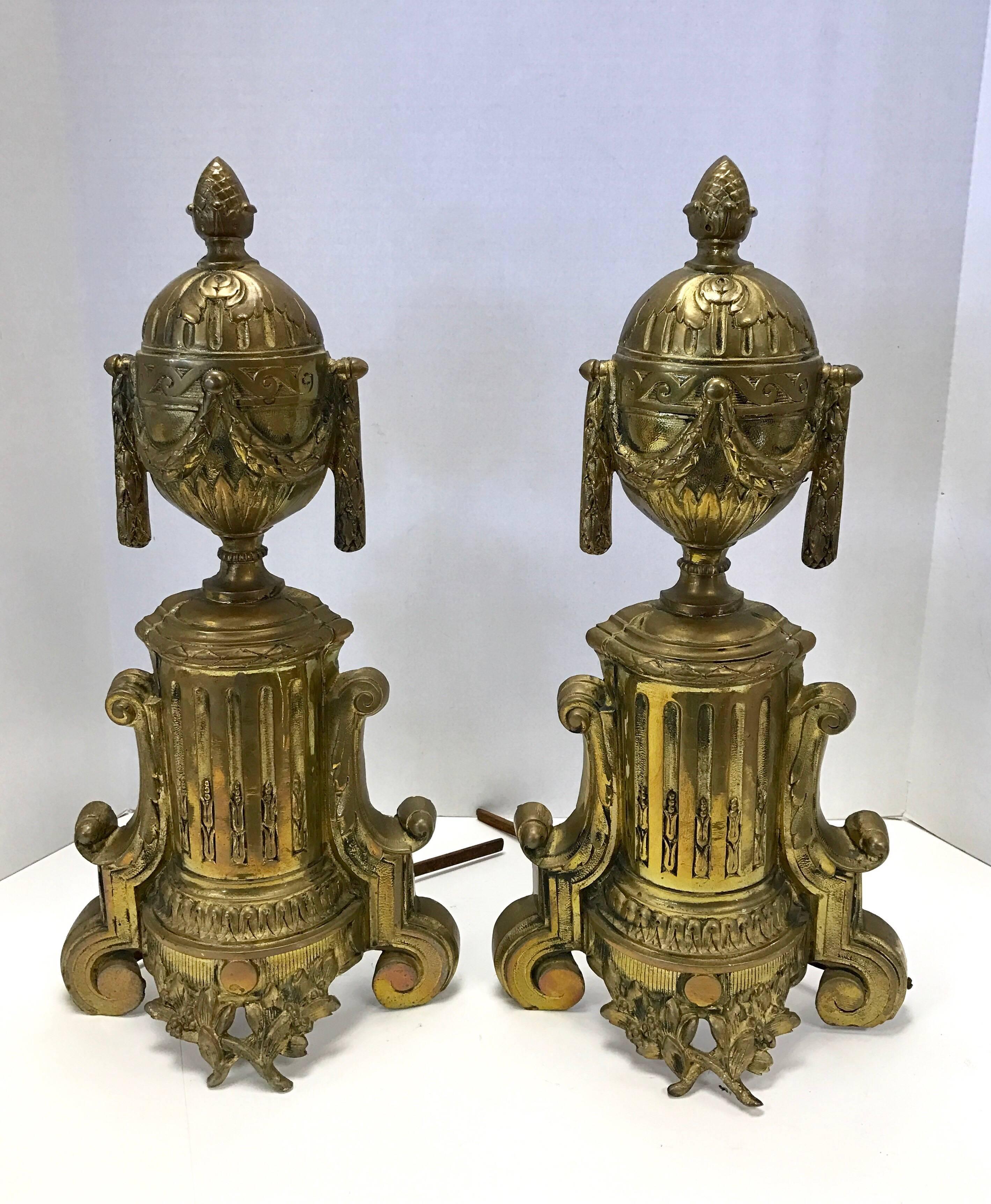 A pair of French cast brass chenets with draped urn detail on column supports. Includes matching fender.
Fender dimensions are 36 inches long by 6 inches tall; dimensions for andirons are below.