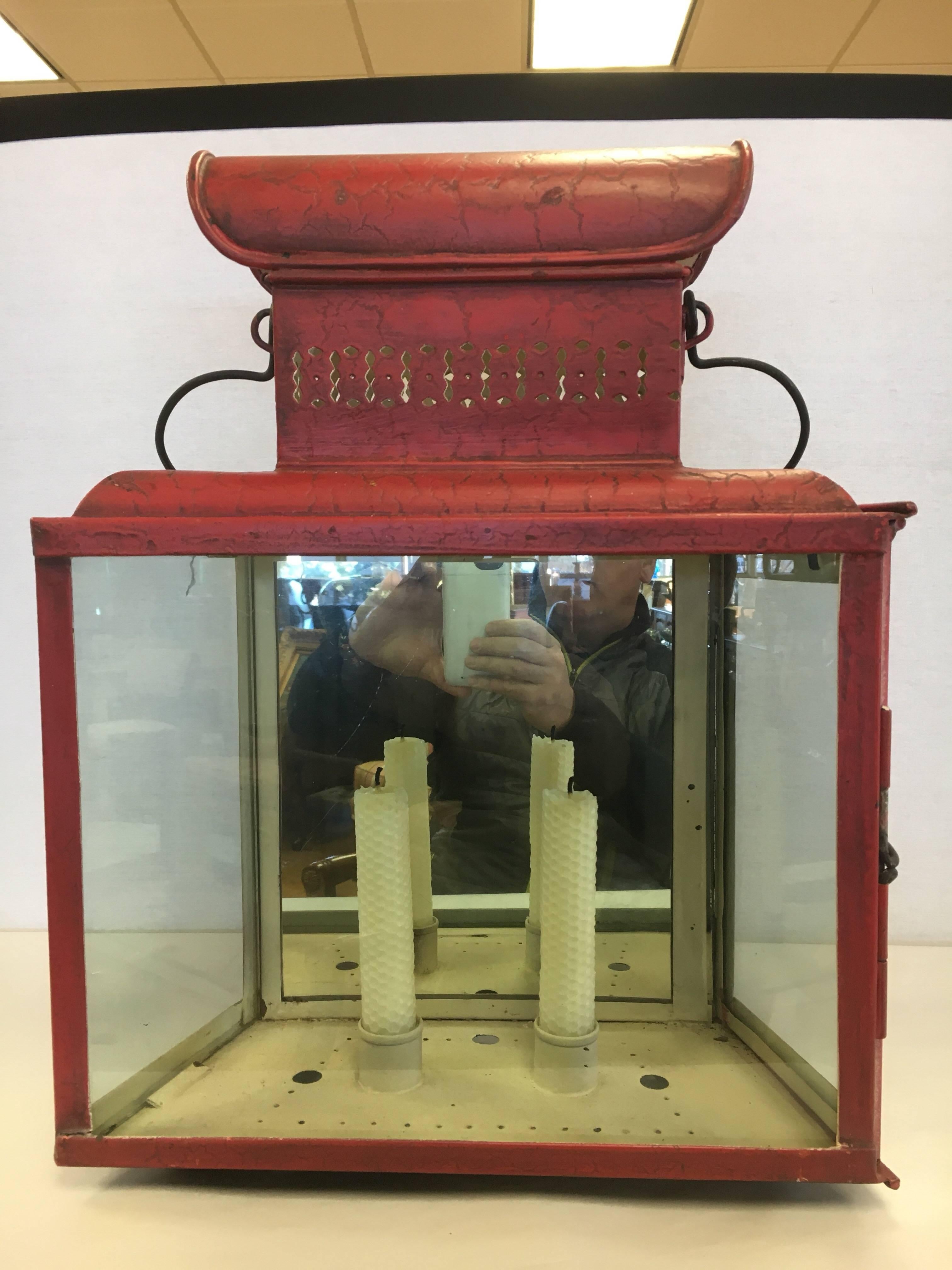 Pair of red tole lanterns sconces with mirrored backs and glass sides. Takes two candles. Non-electrified. Can be hung or sit on a table.