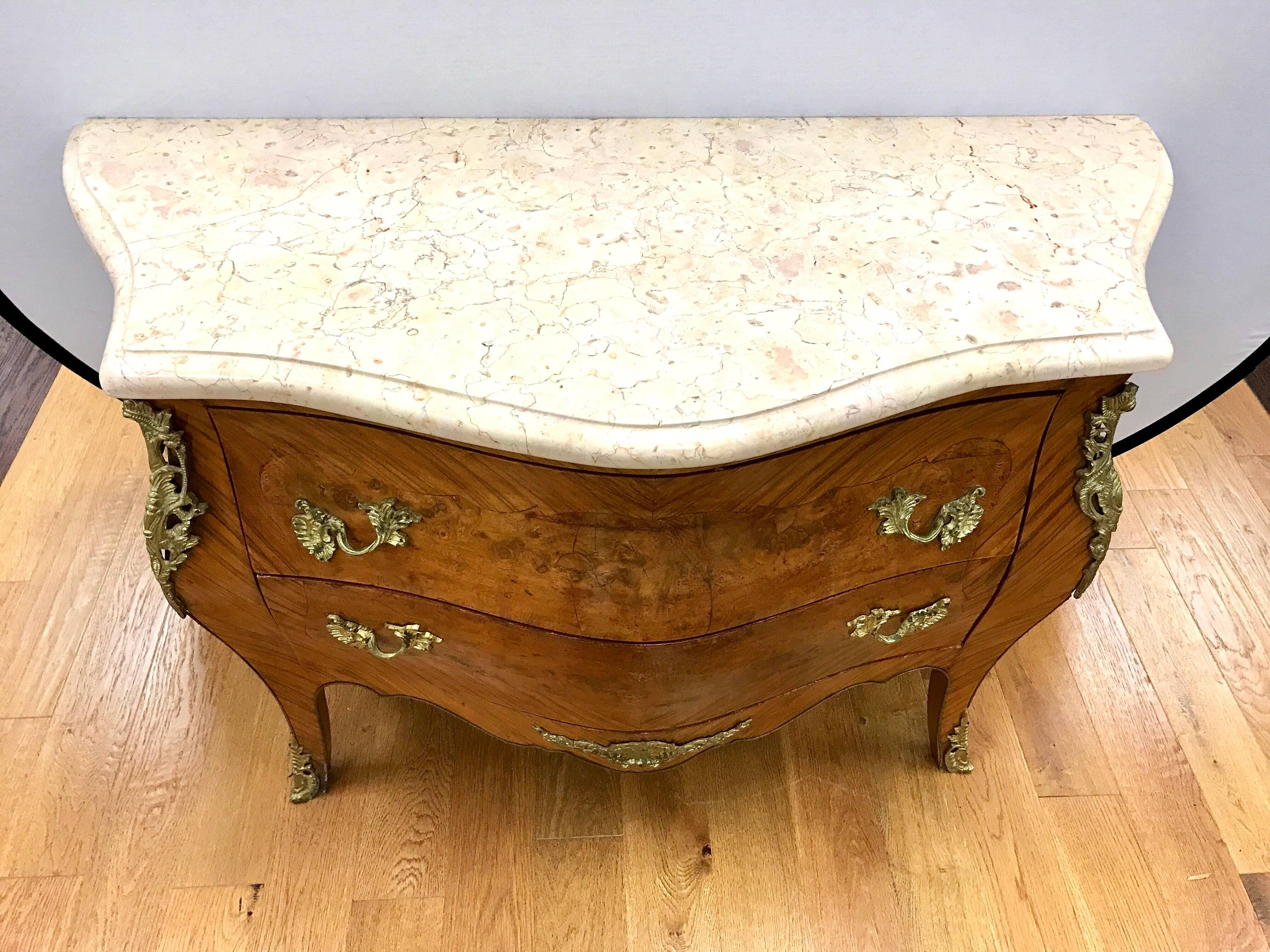 Louis XV style kingwood and mahogany bombe commode with a cream marble top with bronze ormolu mounts.