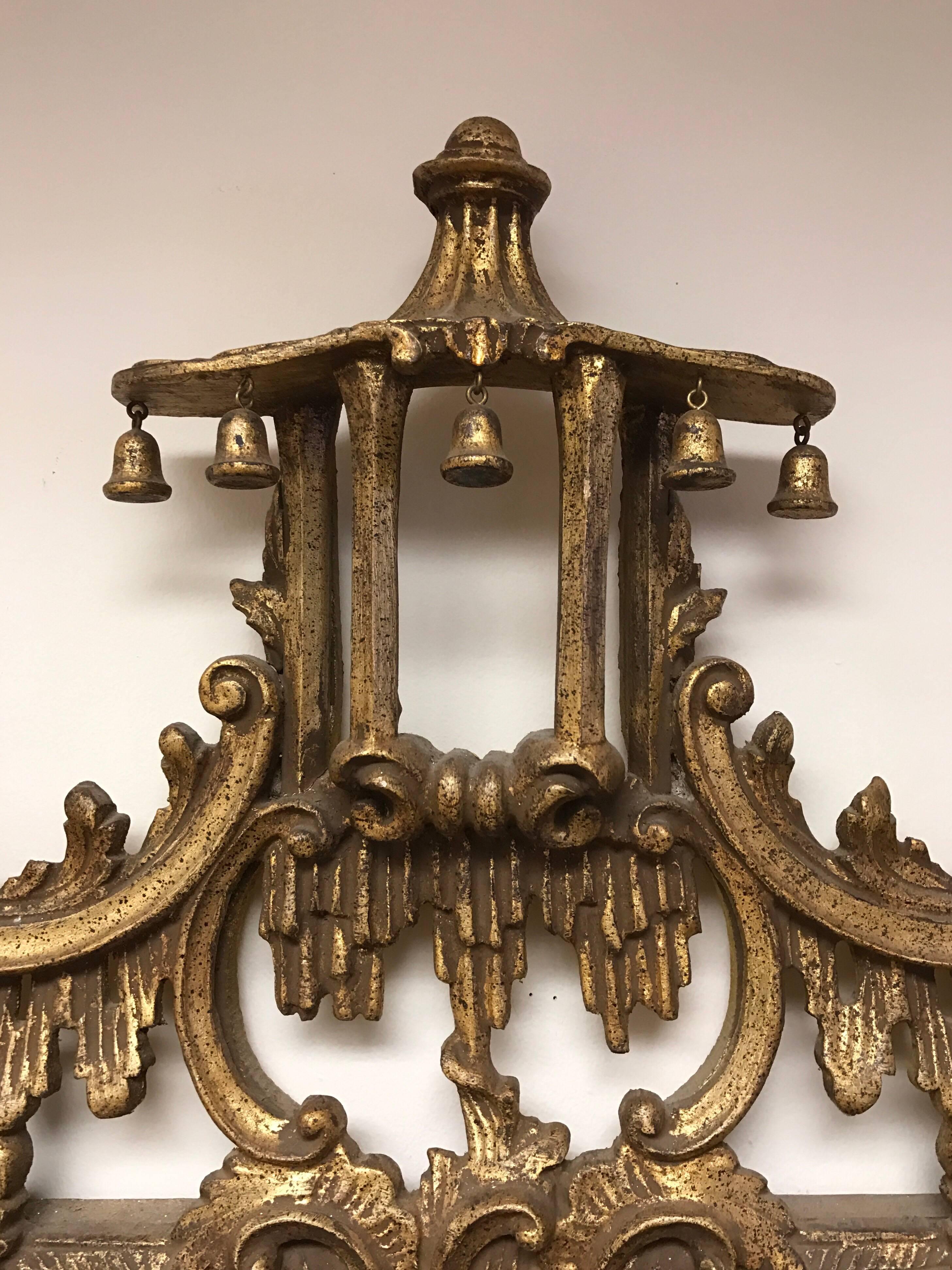 Original intricately carved chinoiserie pagoda mirror with gilt wood. Features carved foliate detail all around and hanging bells below the top of the pagoda steeple. Vintage Chinese Chippendale at its very best. Made in Italy.