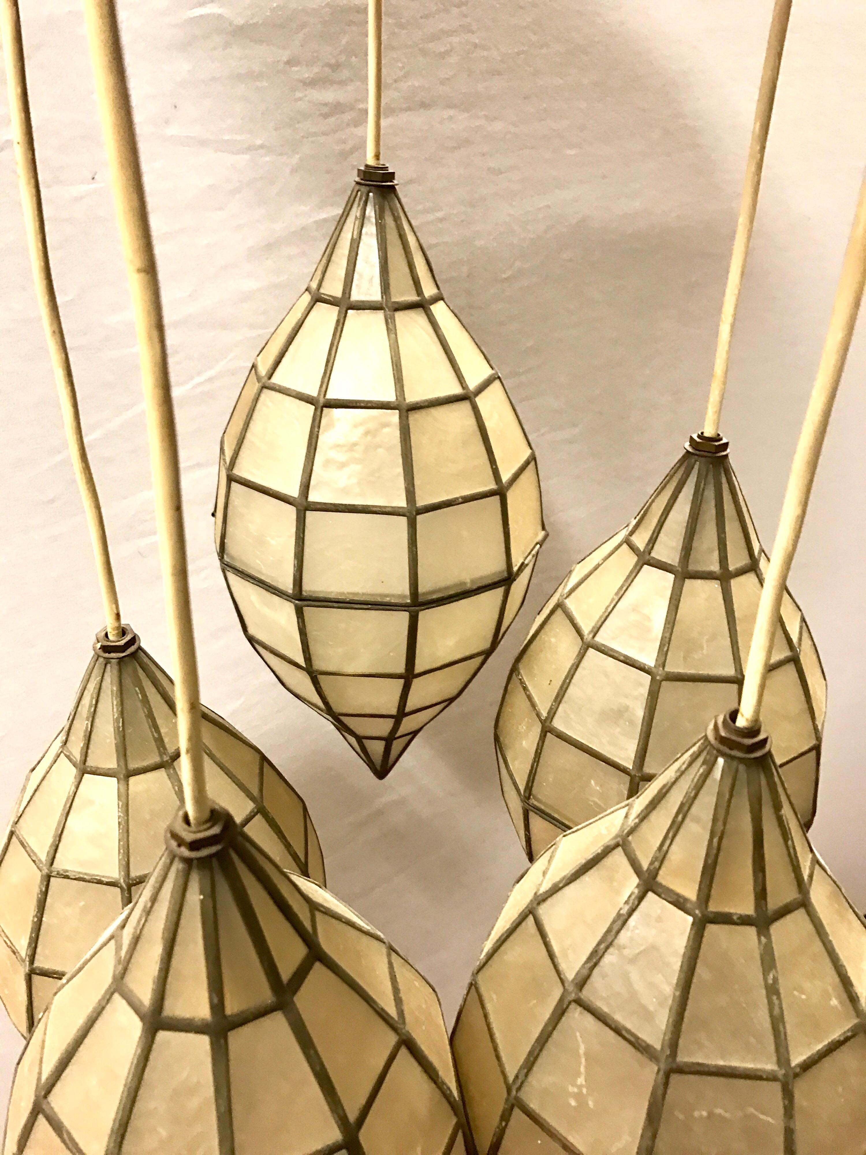 Unusual circa 1970s chandelier with five pendant mother-of-pearl and brass lanterns. Each one opens in the center and is suspended by a white wire that hangs from a round brass ceiling cap. Wire height is adjustable for each. Lanterns are 12 inches