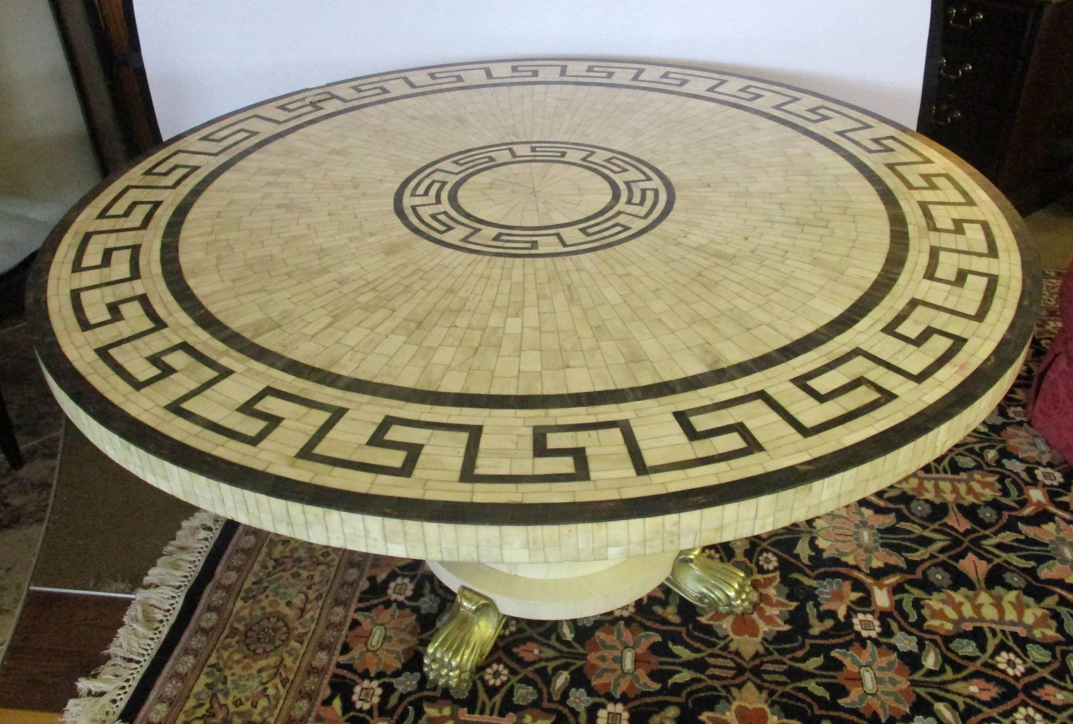 Magnificent one-of-a-kind custom round dining or center table in a mosaic of black and white bone inlay in a Greek key pattern. Cream round would base has four brass paw feet with hidden castors for ease of movement.