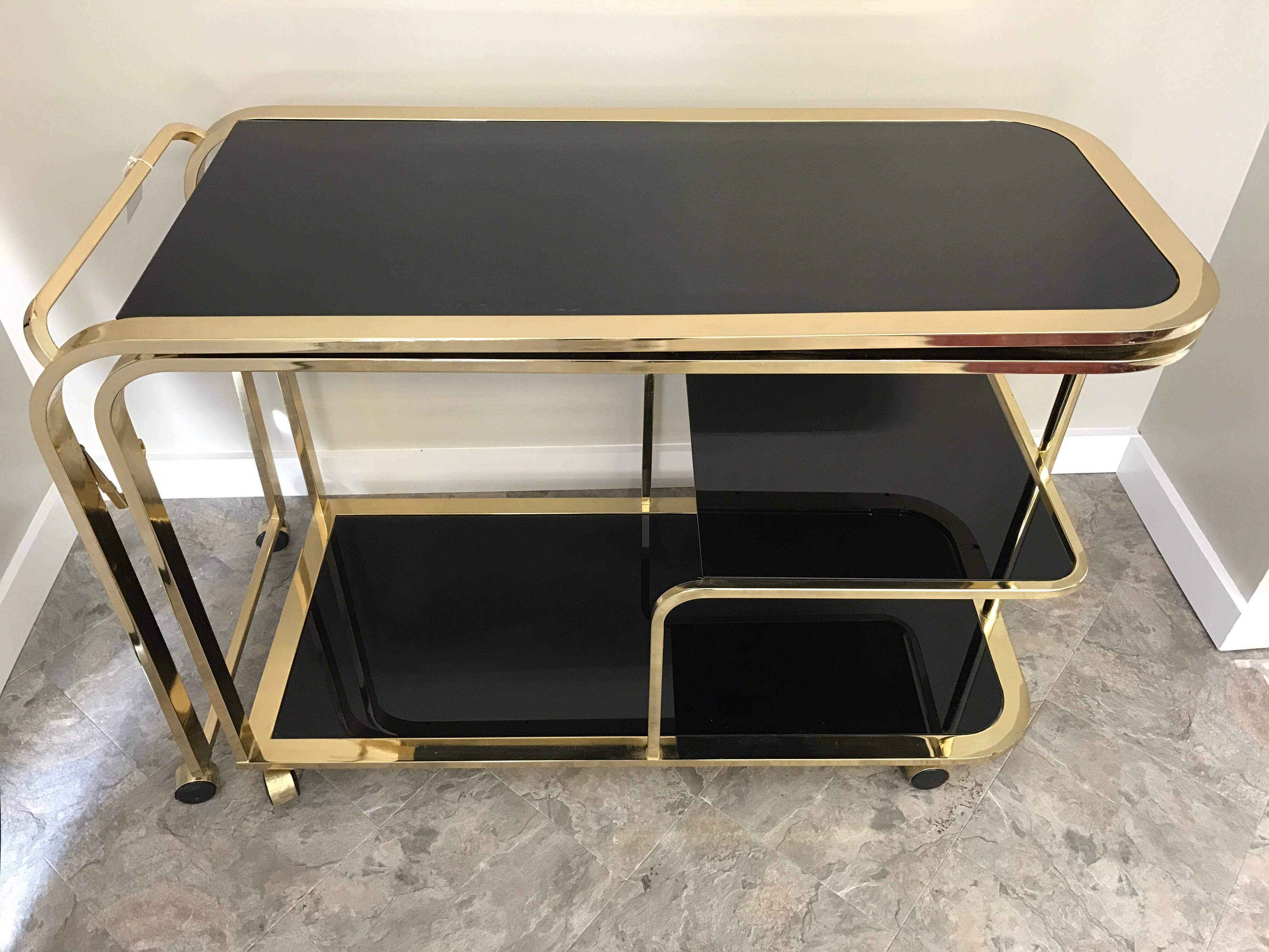 Coveted early 1970s black glass and brass bar or tea cart designed by Milo Baughman for the Design Institute of America. This unique rolling cart can expand into an L-shape and is 87 inches wide when fully expanded. The rare color scheme makes this