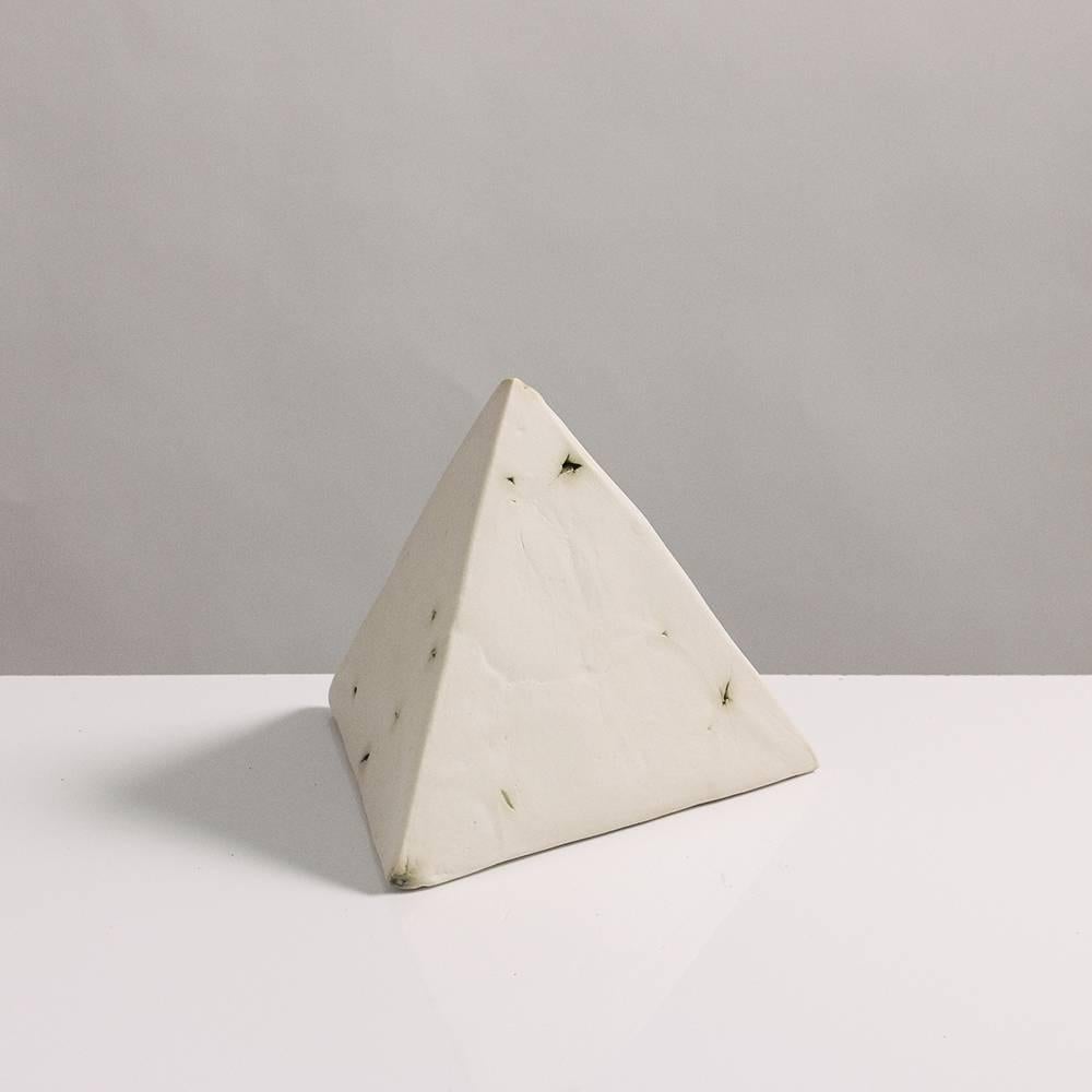 This sculptural geometric tetrahedron is handcrafted from slabs of unglazed white porcelain with highly individual black oxide burnout detailing, giving each of its four sides a unique textural matte finish. The organic texture contrasts with the