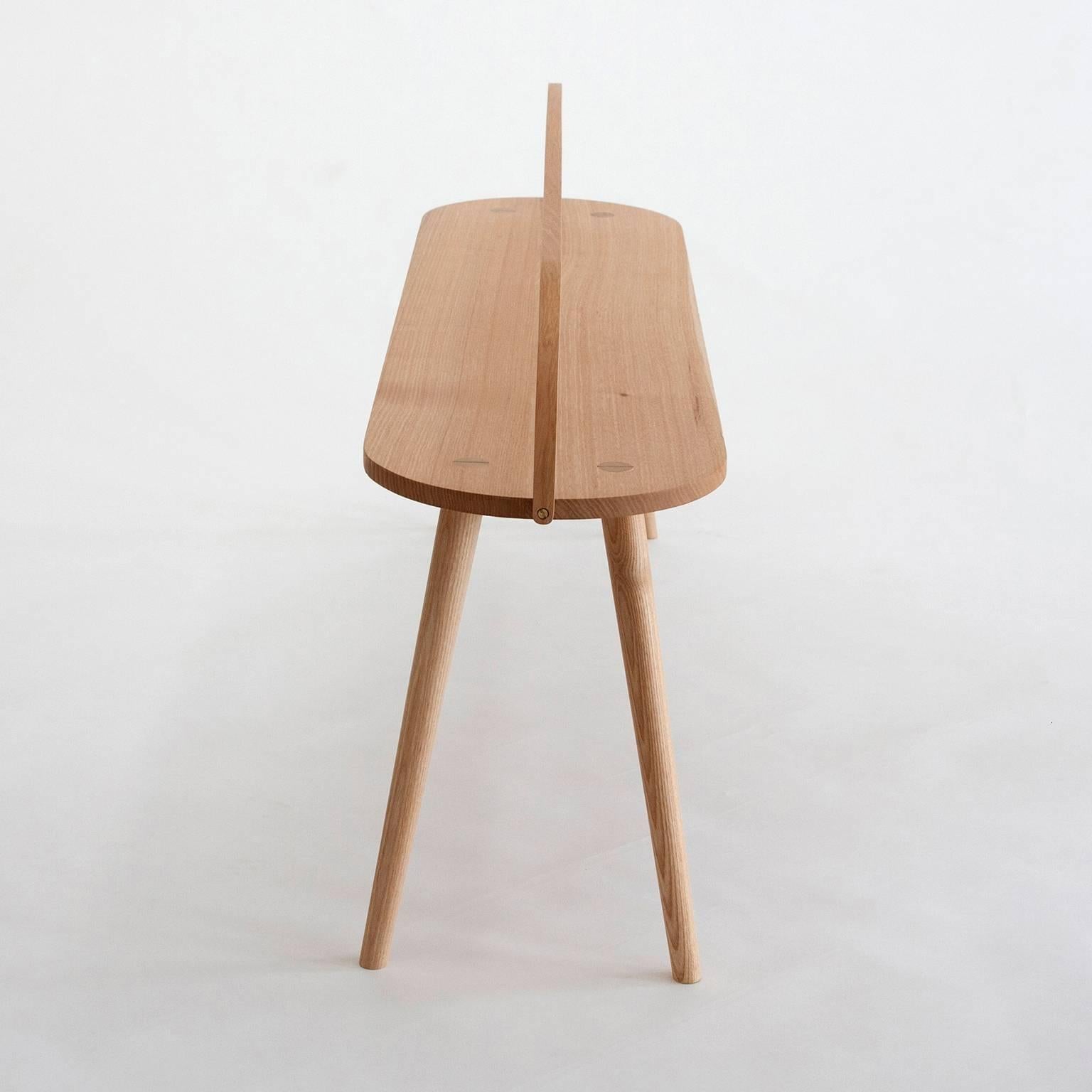 Le tabouret Bucket Bench est la plus longue des quatre versions de la collection Bucket Stool, une famille de meubles en frêne massif dotés de poignées en bois courbé. Le Bucket Bench est une pièce polyvalente, excellente comme banc de salle à