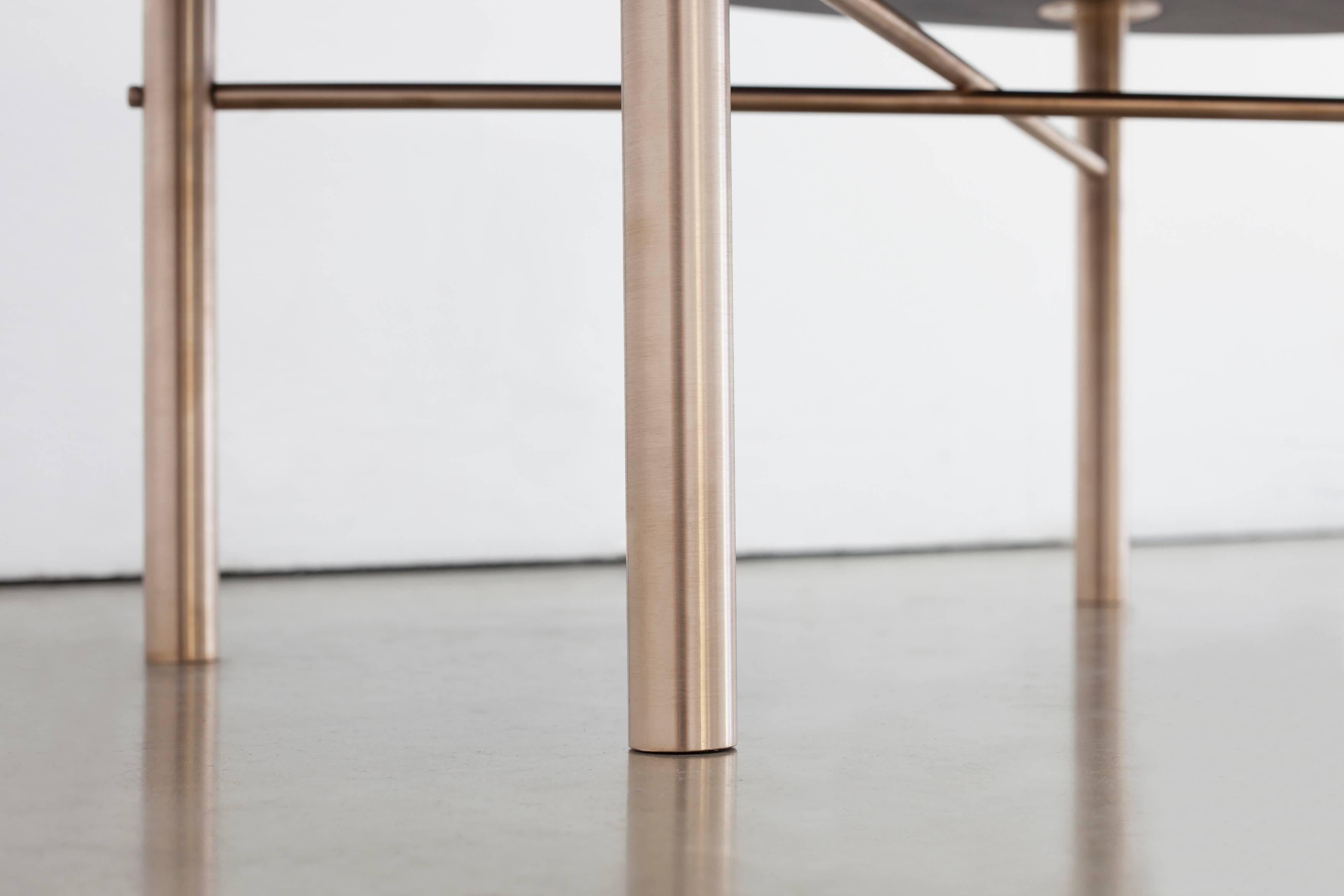 La table basse Connect est fabriquée en bois dur domestique carbonisé et laqué et en bronze massif. Sa conception est une référence visuelle au processus de fabrication. Les qualités de base des matériaux sont présentées simplement afin de créer un