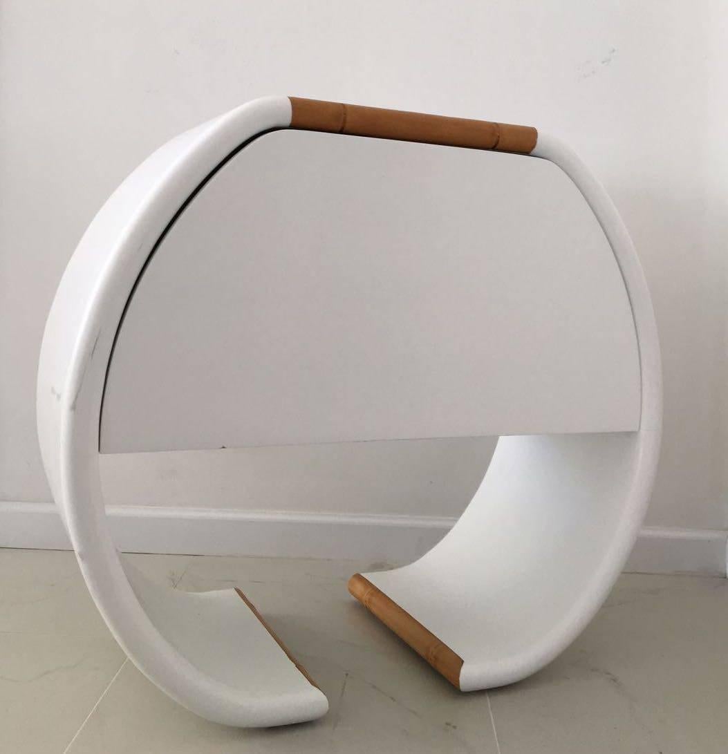Beautiful white, oval-shaped nightstand with bamboo details. Has a push-release front door compartment. It could be easily used to hide electrical equipment, as it has a small, circular opening in back to pass electrical cables.