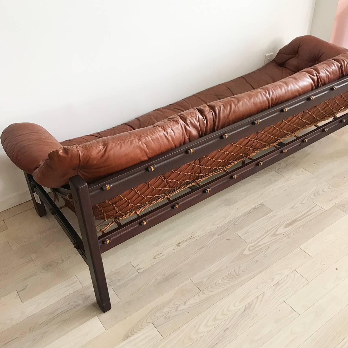 The Amazonas sofa designed by French designer Jean Gillon inspired by and techniques of Brazilian fishermen's boats and nets. Circa 1960s. 
Cognac colored tufted leather upholstery perfectly worn and aged. Rope hammock sling support, against