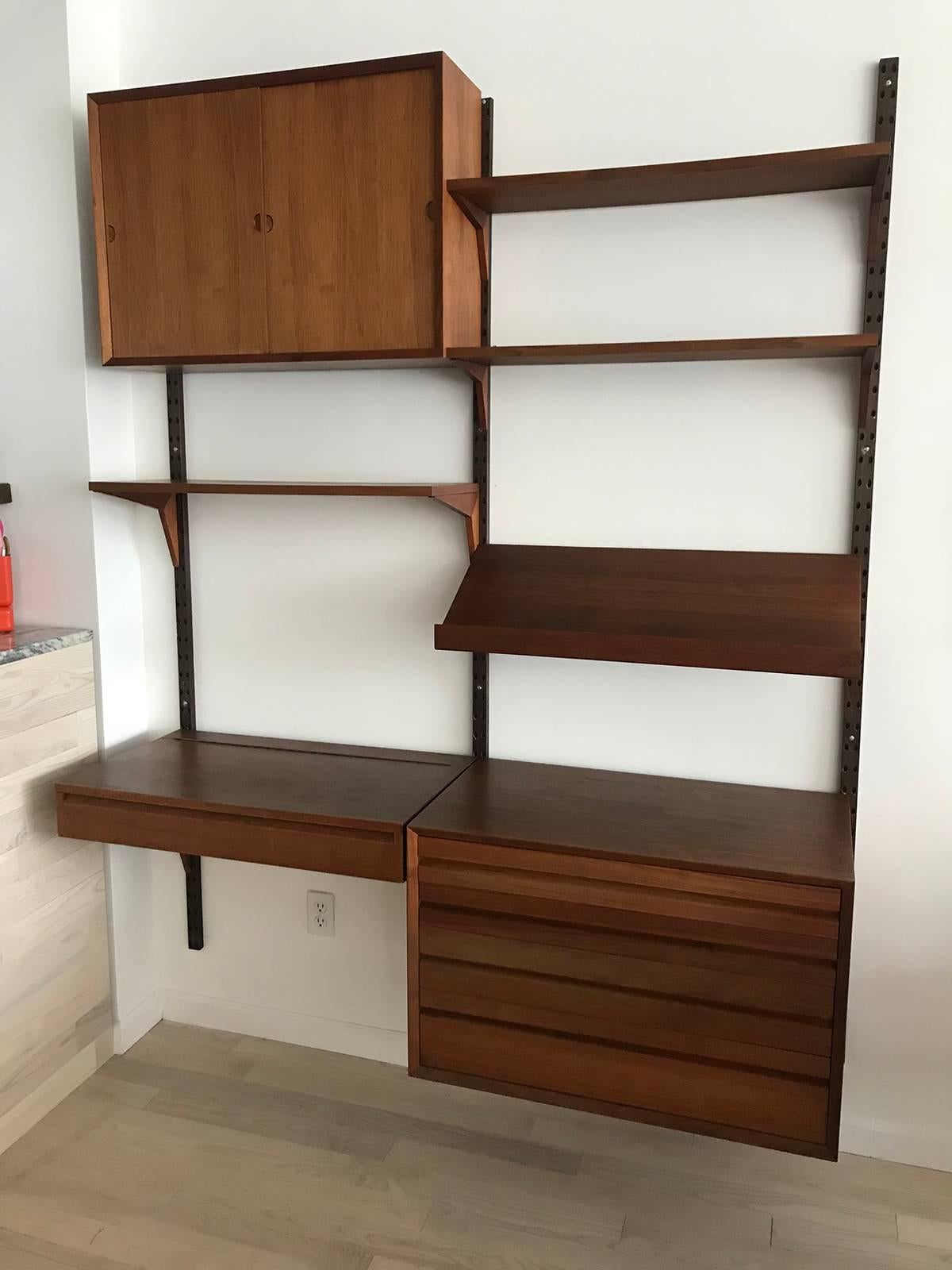 Stunning and timeless teak Danish wall unit that modular by Designer Poul Cadovius. You can set up as you wish. There is a section with four drawers. A desk / vanity section that flips up and has mirror under neath.3 shelves and sliding door