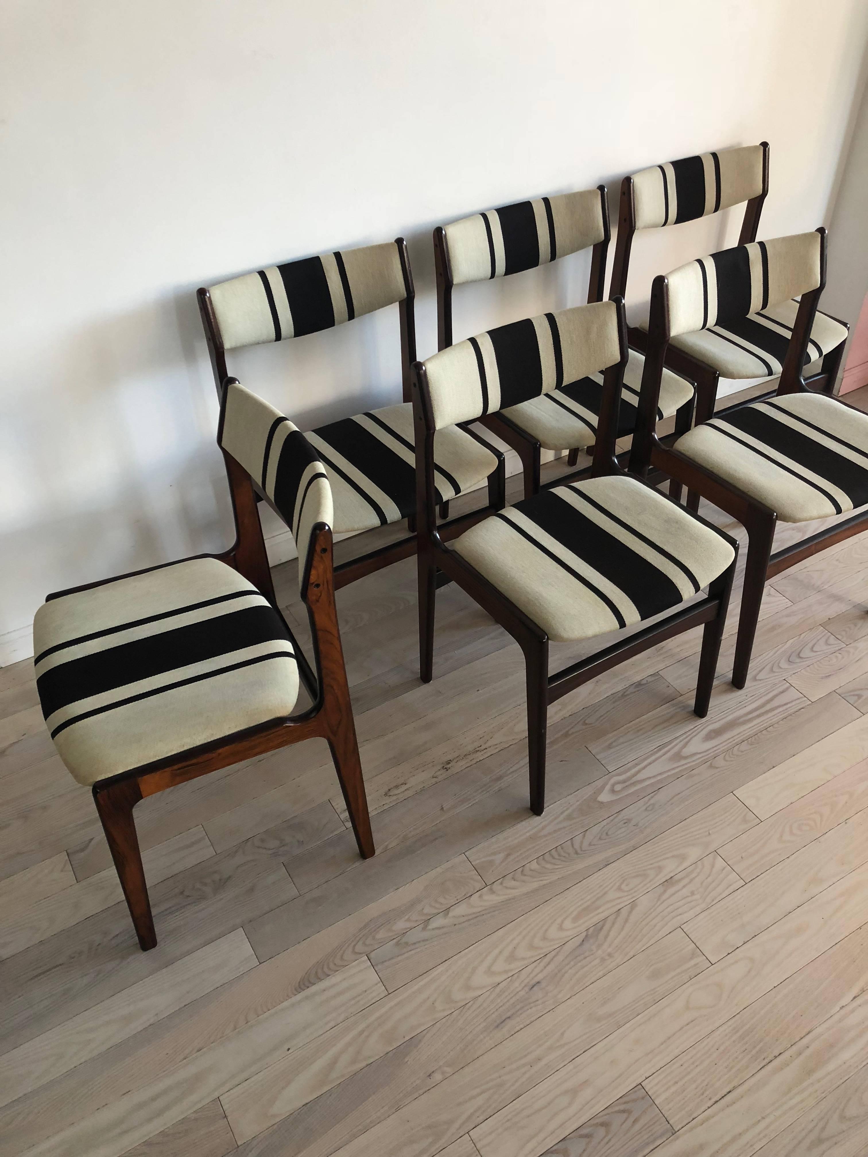 Beautiful rosewood frame with striped upholstery. Sold as a set of six dining chairs. Excellent condition with mild staining to the upholstery from use and age. Made in Denmark. 

Seat height measures 18.5