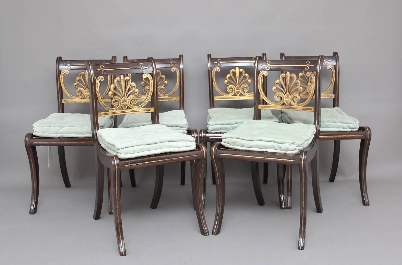 A set of six 19th century simulated rosewood and gilt sabre leg dining chairs, the top and side rails having gilt inlay with the centre rail decorated with a gilt ornate flower pattern, the chairs having a cane seat with a drop in fabric cushion,