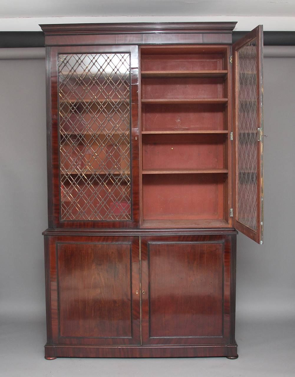 Early 19th century large Regency mahogany bookcase, the moulded cornice above a pair of glazed doors with brass grilles of intricate form, opening to reveal four adjustable shelves, with fluted columns running down from each side of the bookcase,