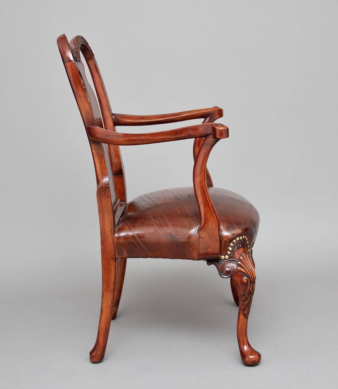 An elegant early 20th century Queen Anne style child’s walnut open armchair, the wonderfully carved and shaped back splat flanked by curved uprights incorporating carved eagle heads, the elegantly shaped arm supports leading down to a fitted tan