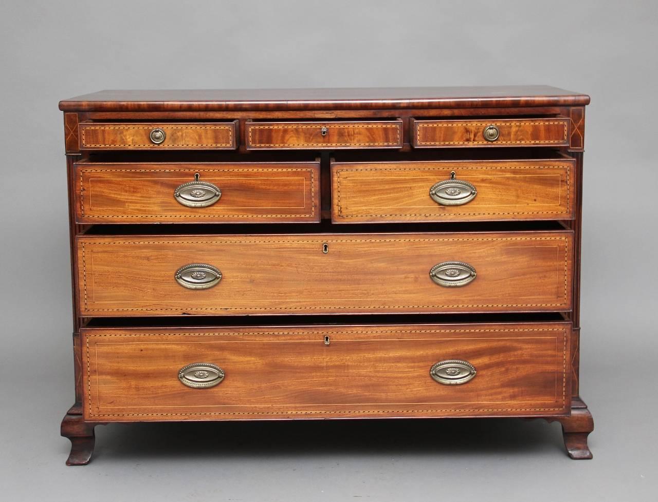 Early 19th century mahogany and chequer line-inlaid chest of drawers, the rectangular top above three small drawers with brass ring handles, and below a combination of two short over two long graduated drawers between fluted stiles, standing on ogee