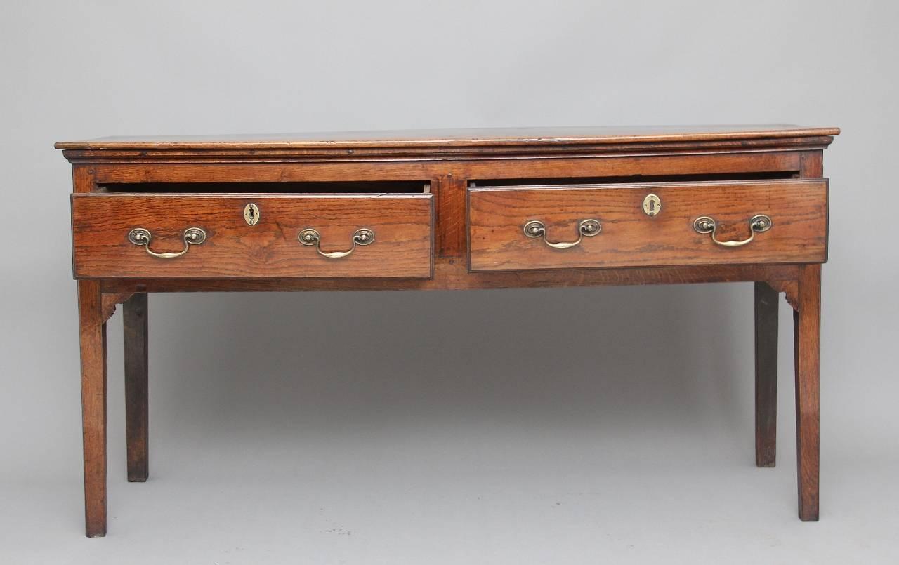 18th century oak dresser base, the moulded edge top above two long oak lined drawers with original brass swan neck handles, standing on square tapering legs, the dresser is in very good condition and has a nice honey color, circa 1780.