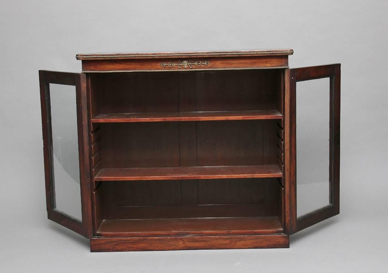 19th century rosewood and ormolu bookcase of good proportions, the rounded rectangular top decorated with ormolu beading along the sides and front edge, the front of the bookcase having various ormolu mounts, patraes and beading, the two glazed