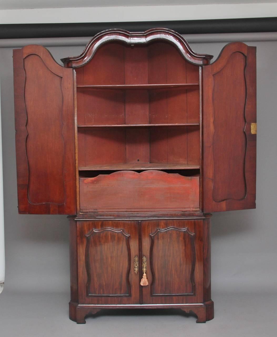 18th century Dutch mahogany corner cupboard with a moulded arched cornice, the top section having two paneled doors with shaped and moulded beading around the panels, opening to reveal three fixed shelves and a drop down flap at the bottom of the