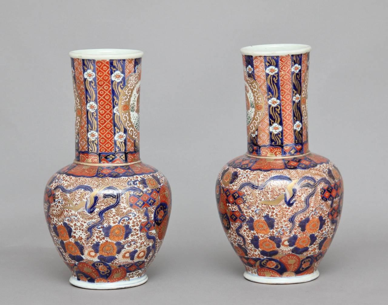 A decorative pair of Japanese, 19th century Imari Porcelain vases with a cylindrical neck, decorated throughout with red, blue and gold glazes upon a white ground, in excellent condition, circa 1880.
 
