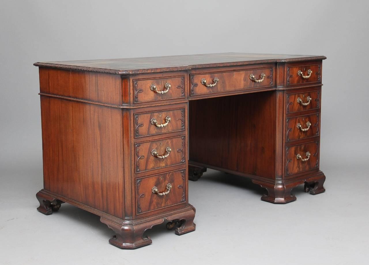Early 20th century Chippendale style mahogany desk with canted corners, the rectangular shaped top with an original green leather writing surface, the top having a carved moulded edge, below with an arrangement of nine graduated mahogany lined