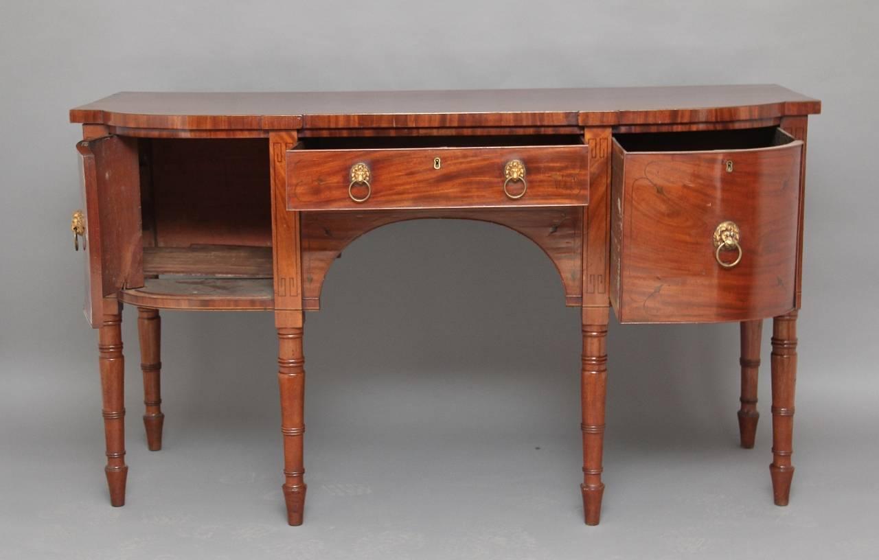 19th century mahogany bow ended sideboard with a cupboard on the left and a large drawer on the right with a drawer in the centre, nicely inlaid with ebony and oak lined, fitted with original lions head handles, standing on lovely turned legs, very