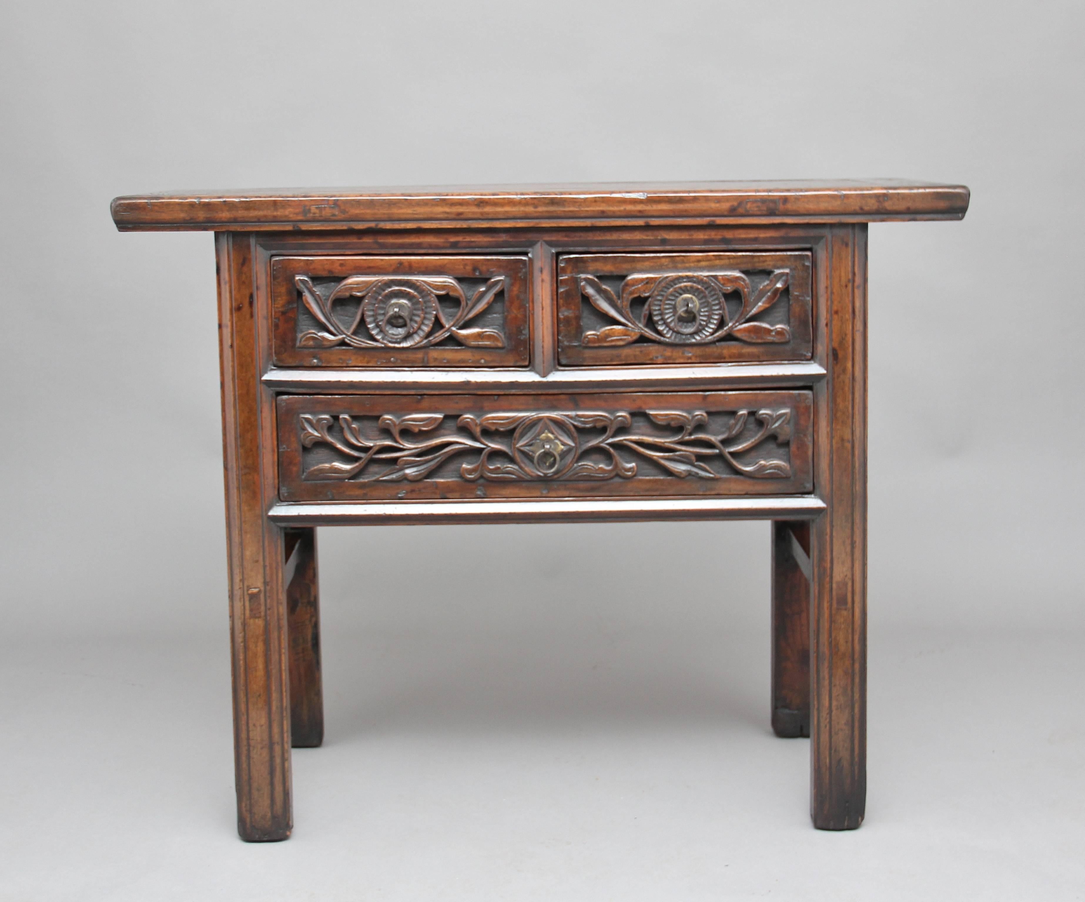 19th century Chinese rustic elm dresser with two short over one long drawer, with the drawer fronts having a carved floral design and original brass ring handles, standing on square legs supported with side stretchers, circa 1880.