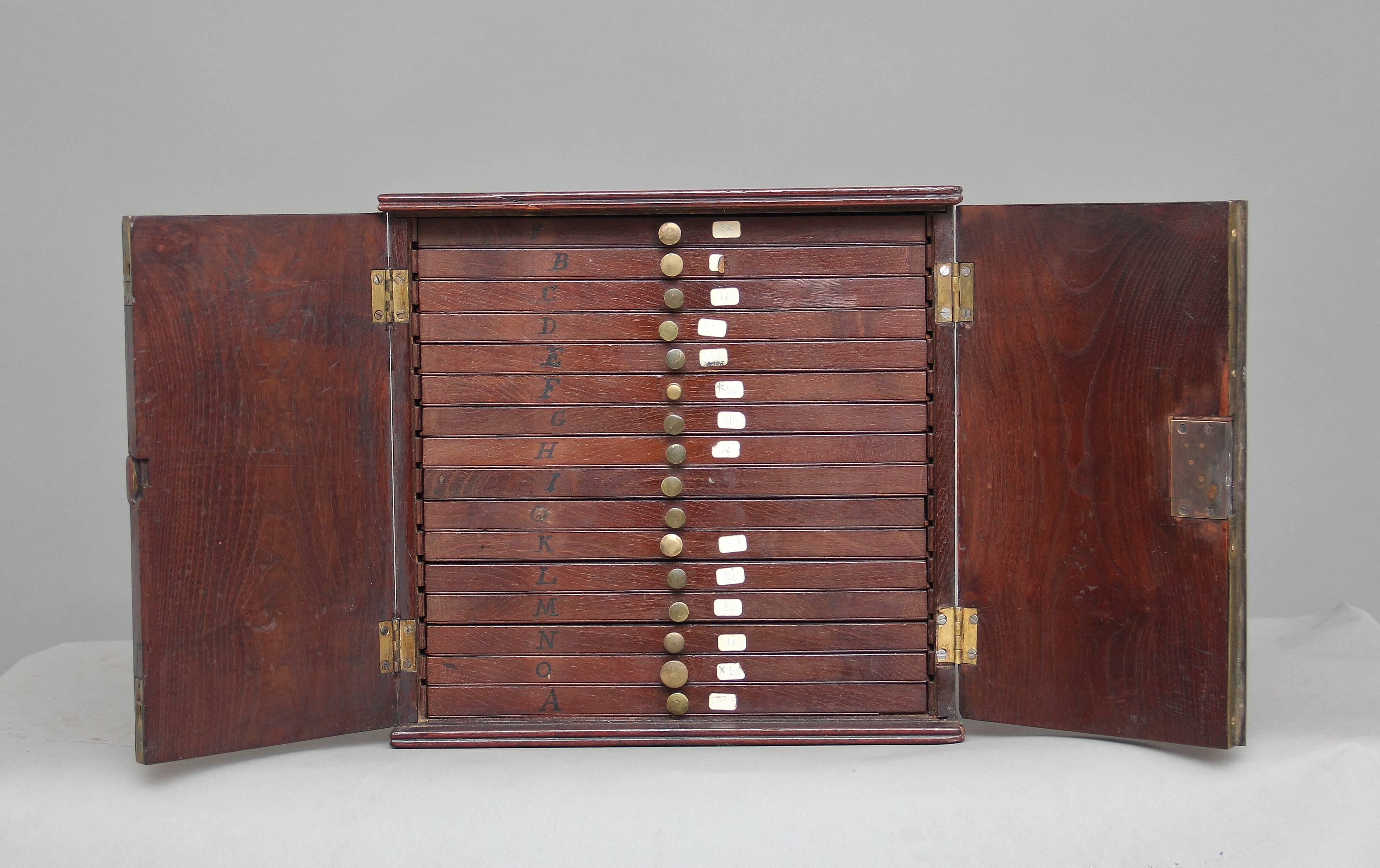 Early 19th century laburnham coin collectors cabinet, the cabinet of good proportions with original brass carrying handles on the sides, with two hinged doors at the front opening to reveal a selection of sixteen drawers, with each drawer having